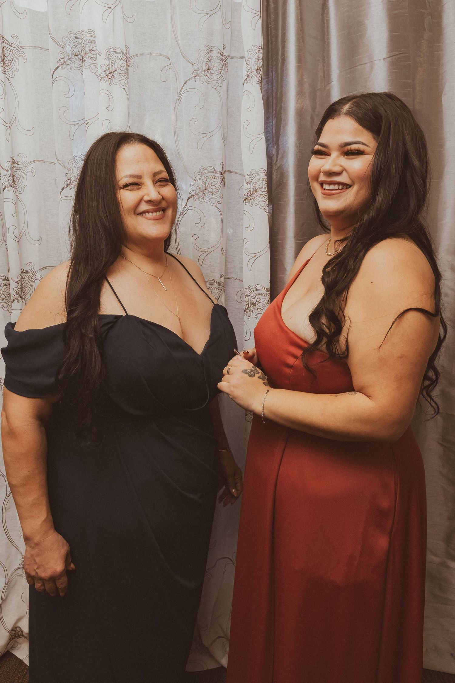 Two women in elegant evening gowns pose together during a formal event.