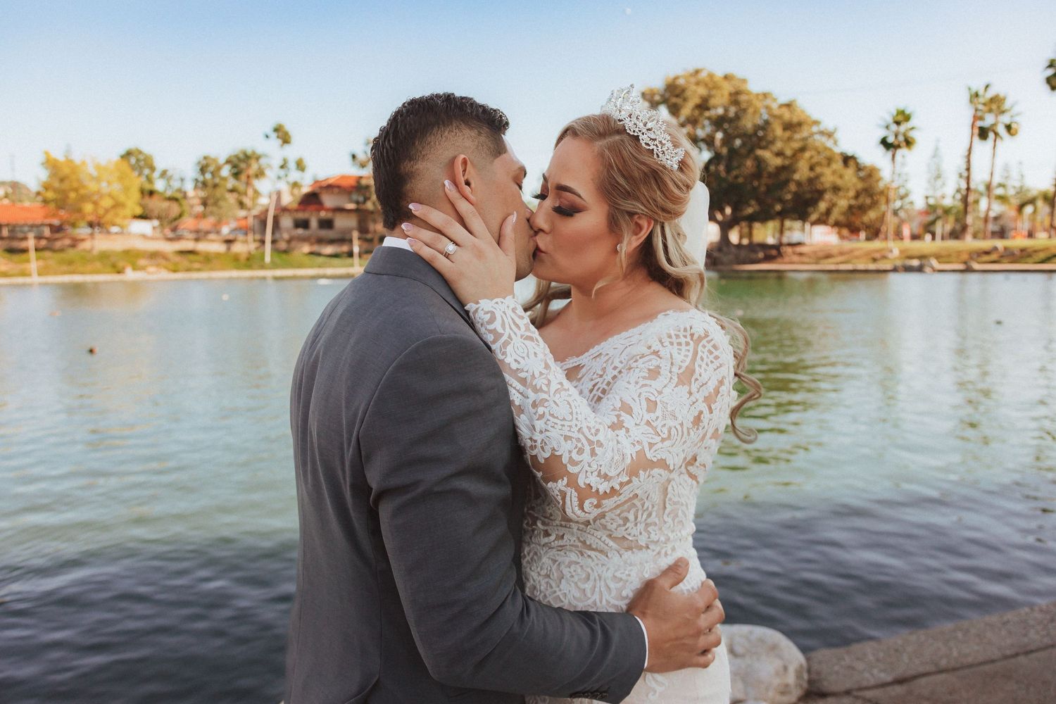 Wedding portrait of couple sharing a tender moment beside a serene lake.