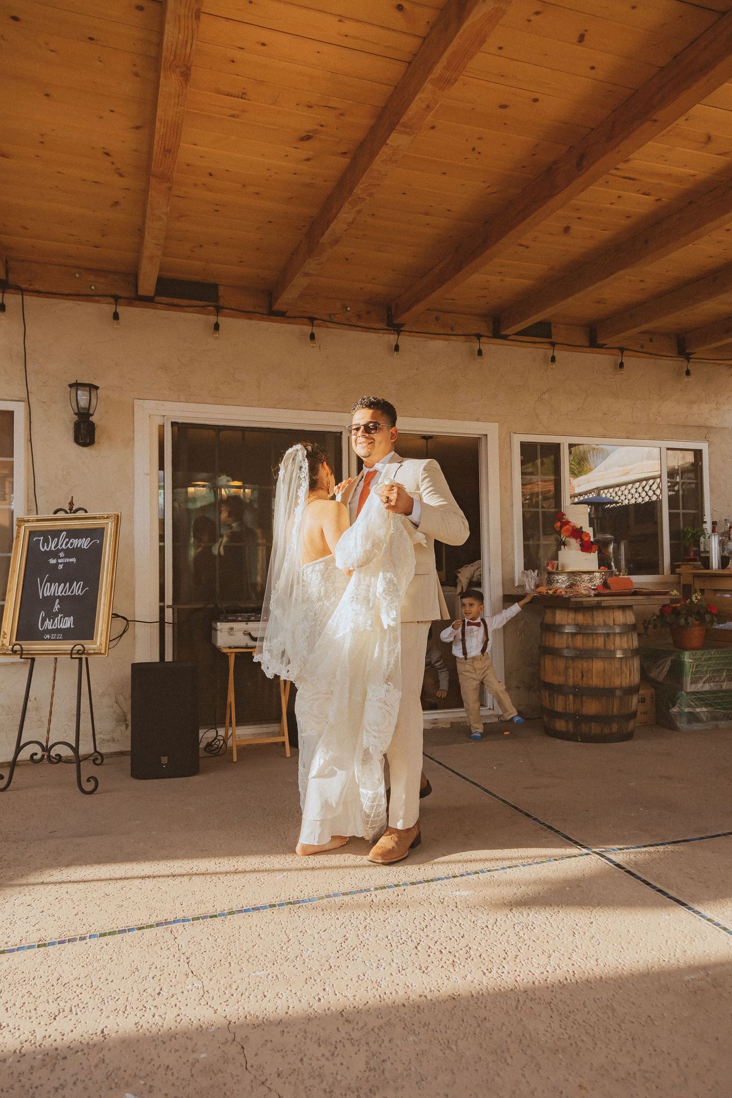 Couple shares their first dance outdoors under wooden beamed patio.