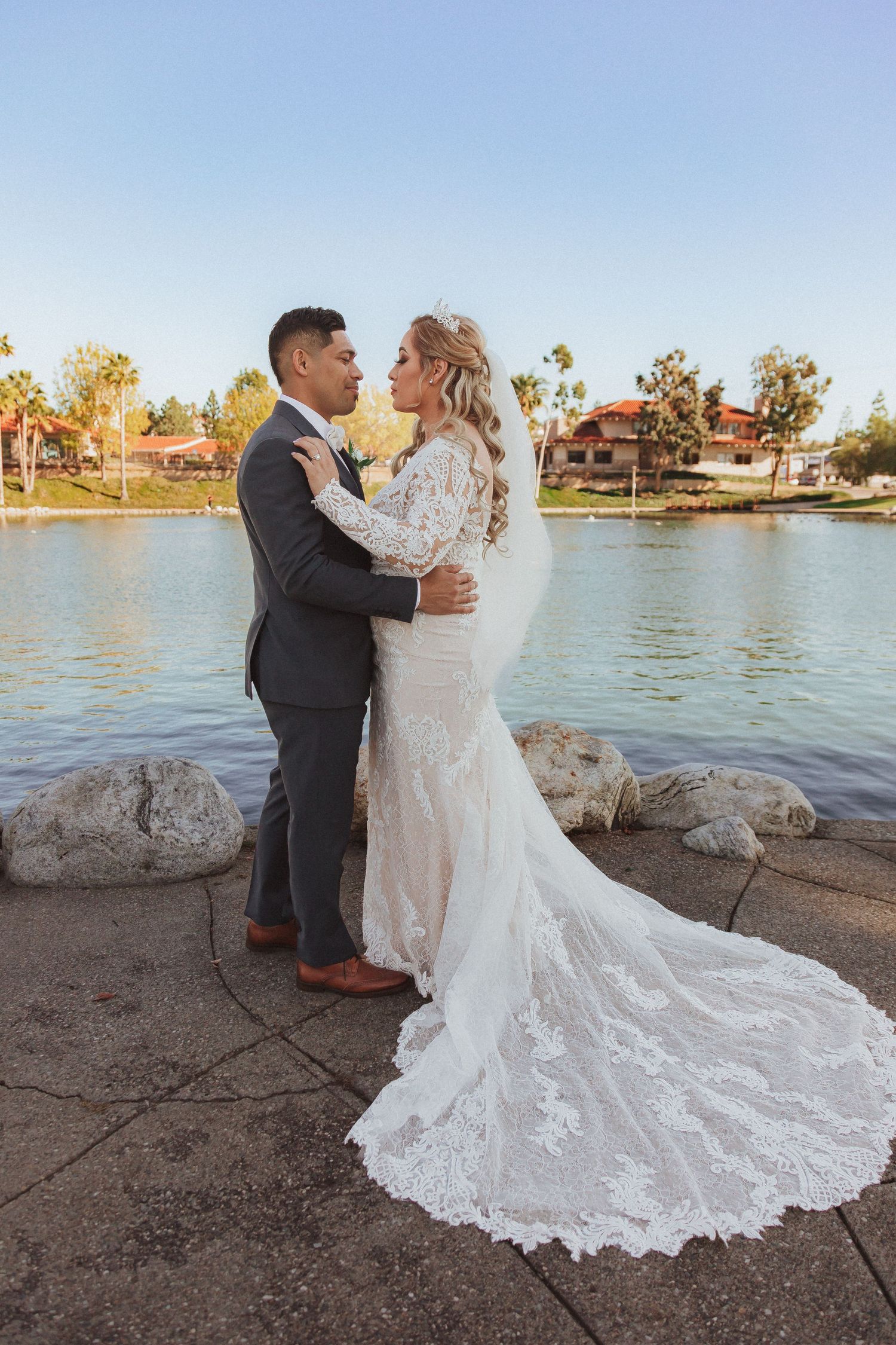 A tender moment between newlyweds beside a serene lake during golden hour.