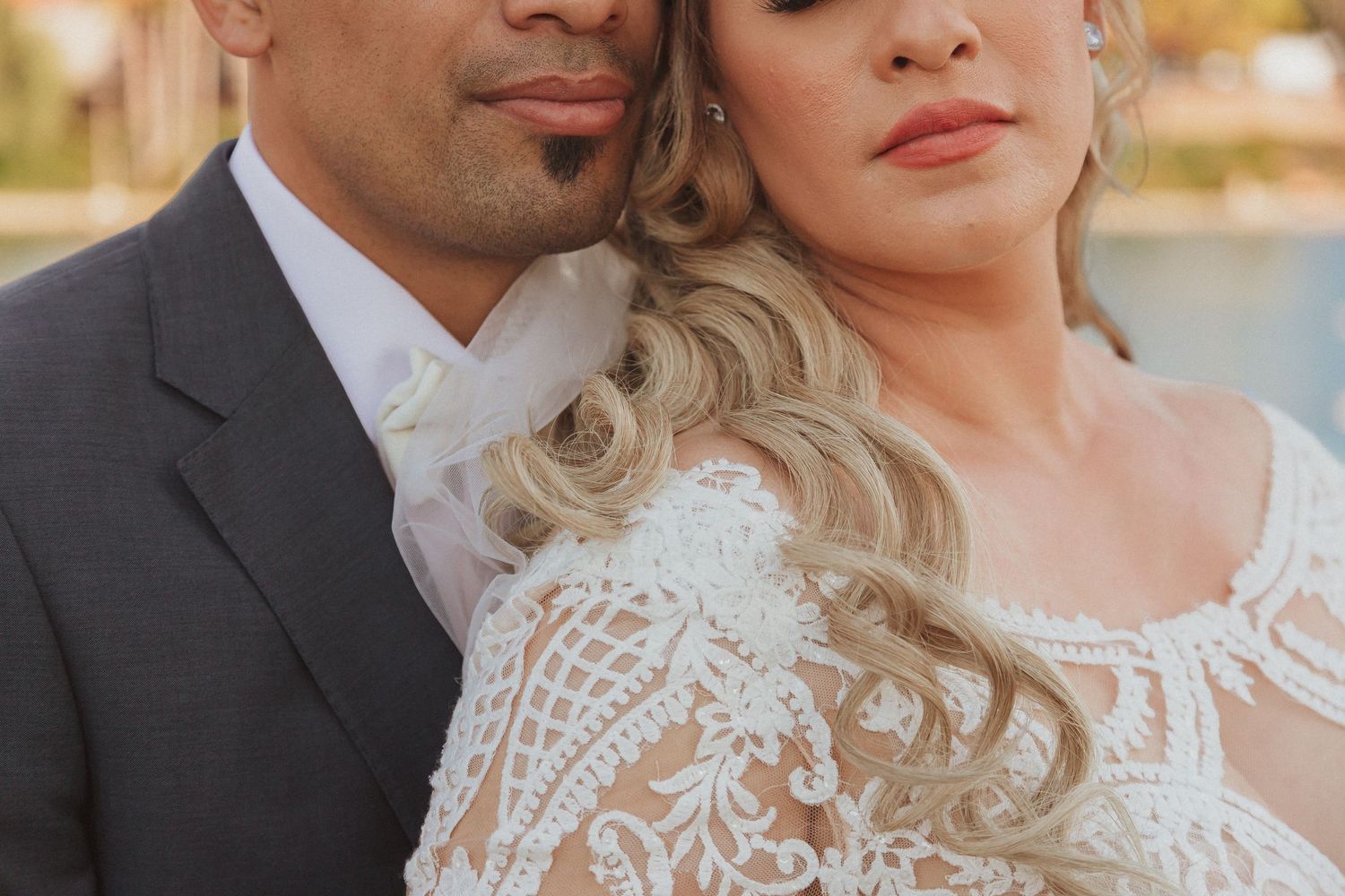 Close-up portrait of couple in sophisticated wedding attire by waterfront.