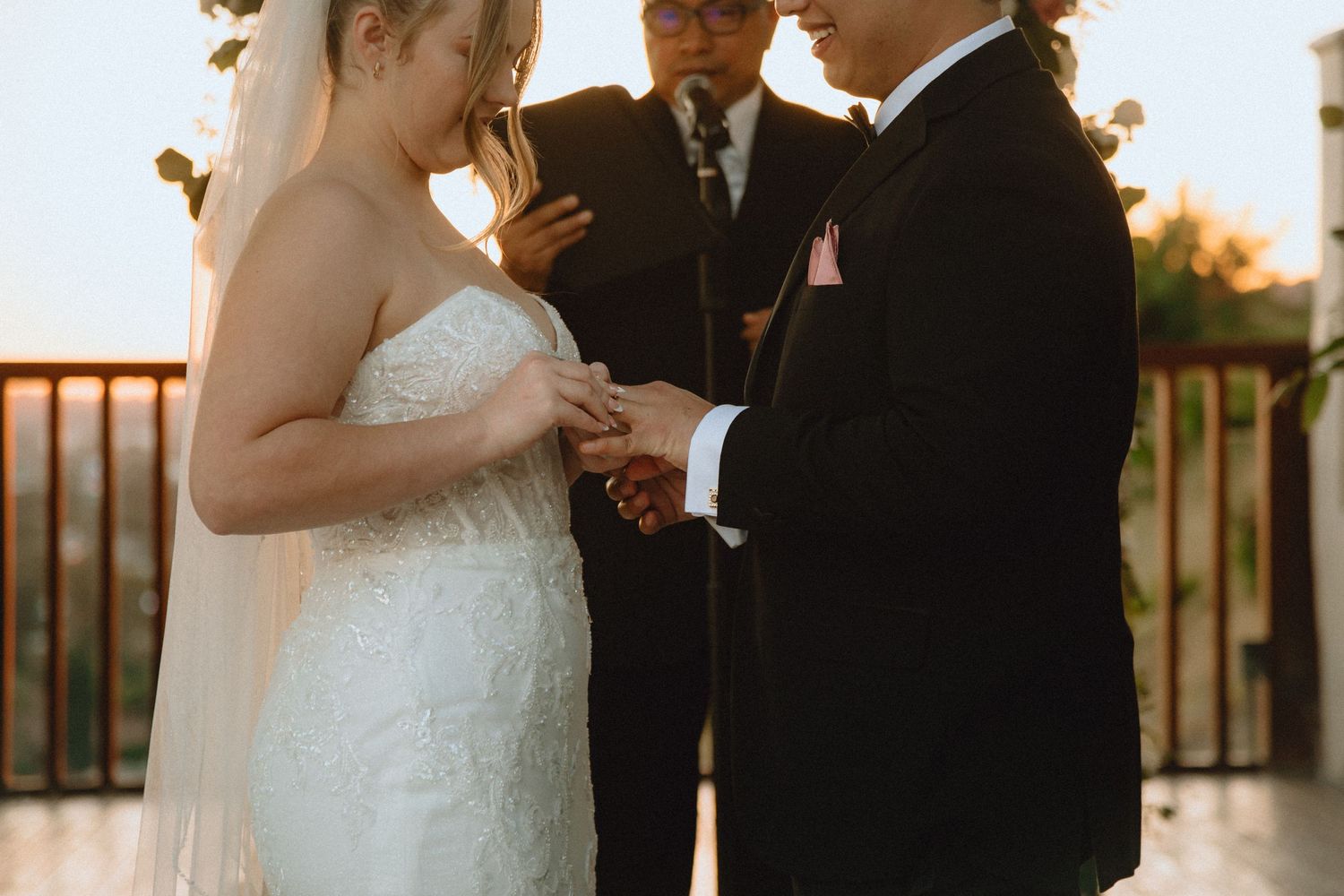 An intimate ring exchange moment during an outdoor wedding ceremony at sunset.