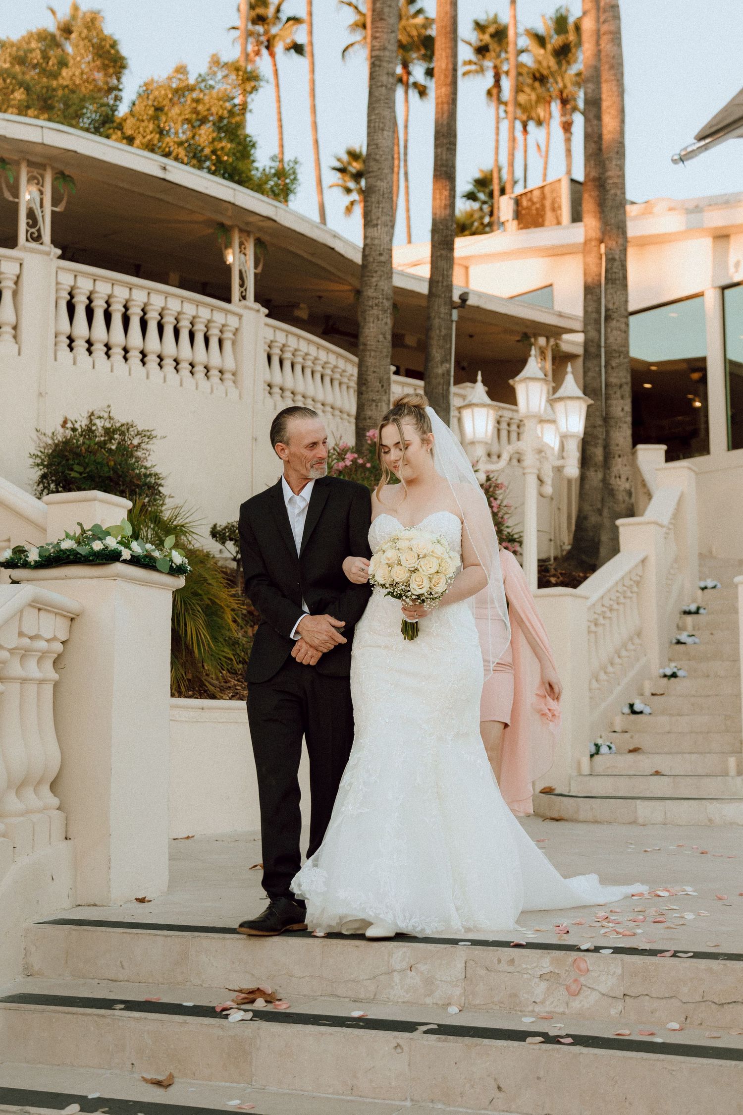 Wedding photograph on grand white staircase with tropical landscaping.