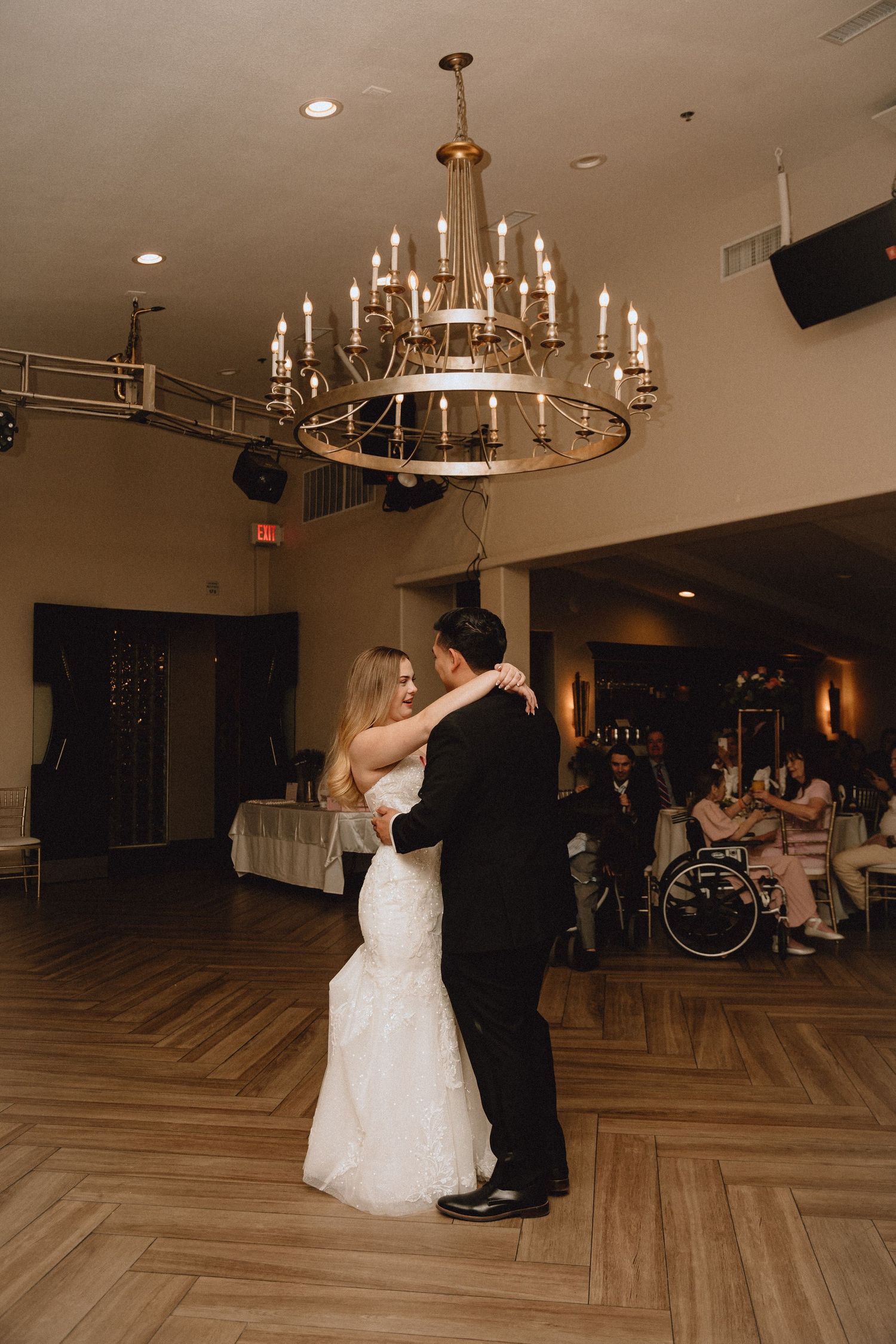A romantic dance between newlyweds under a dramatic chandelier in a reception venue.