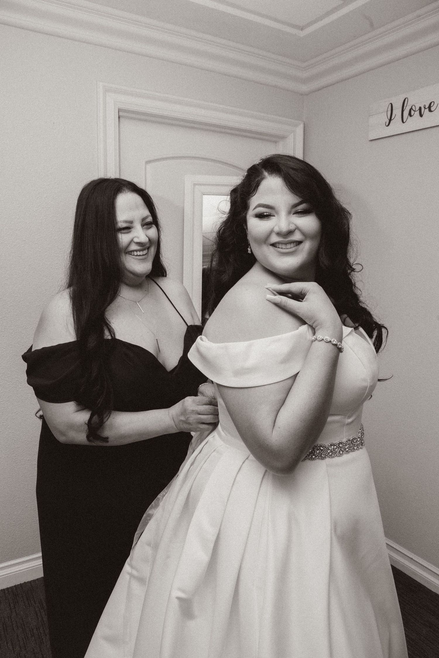 A candid black and white photo showing a heartwarming moment during wedding preparations.