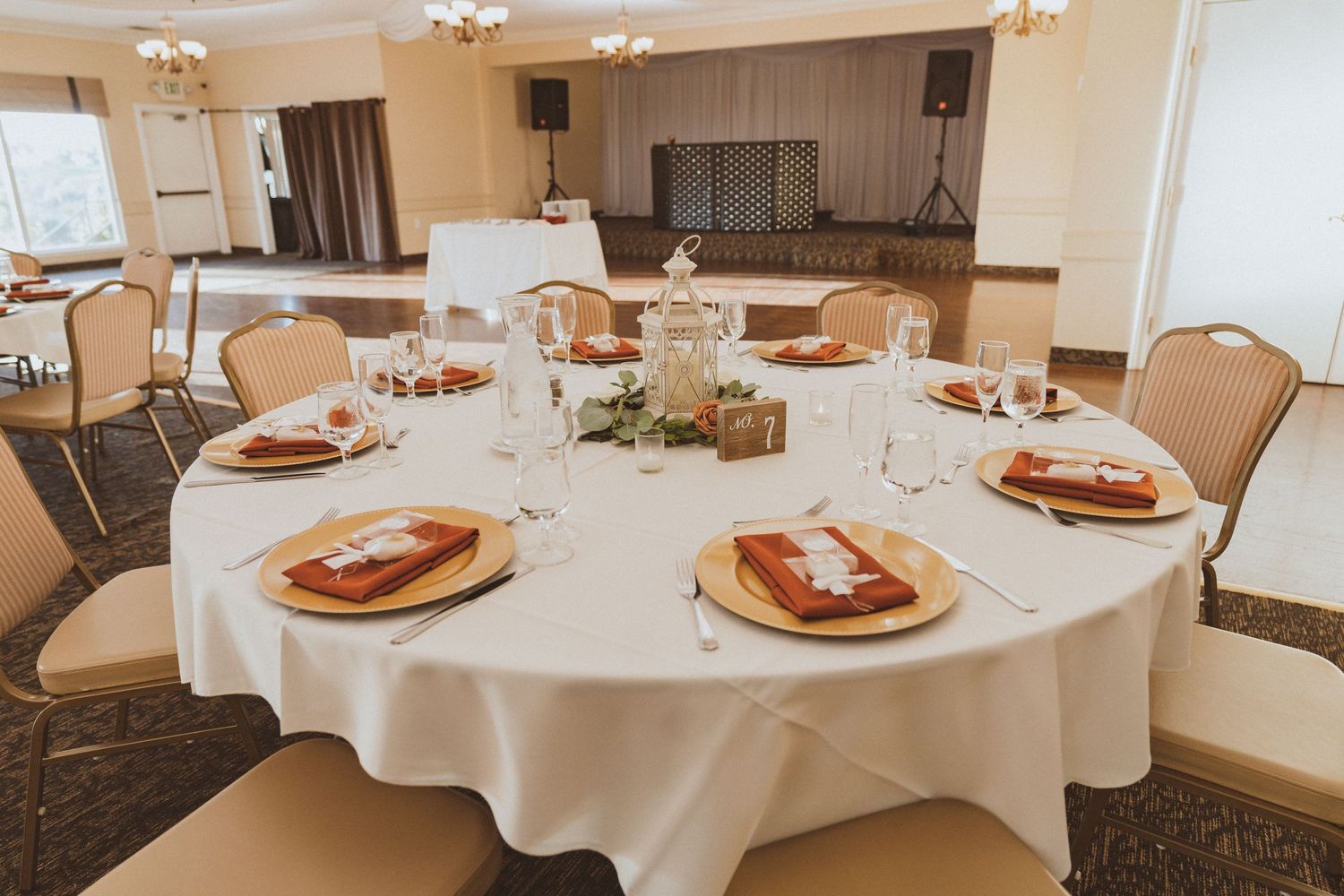 Wedding reception tables with white tablecloths and place settings featuring gold charger plates.