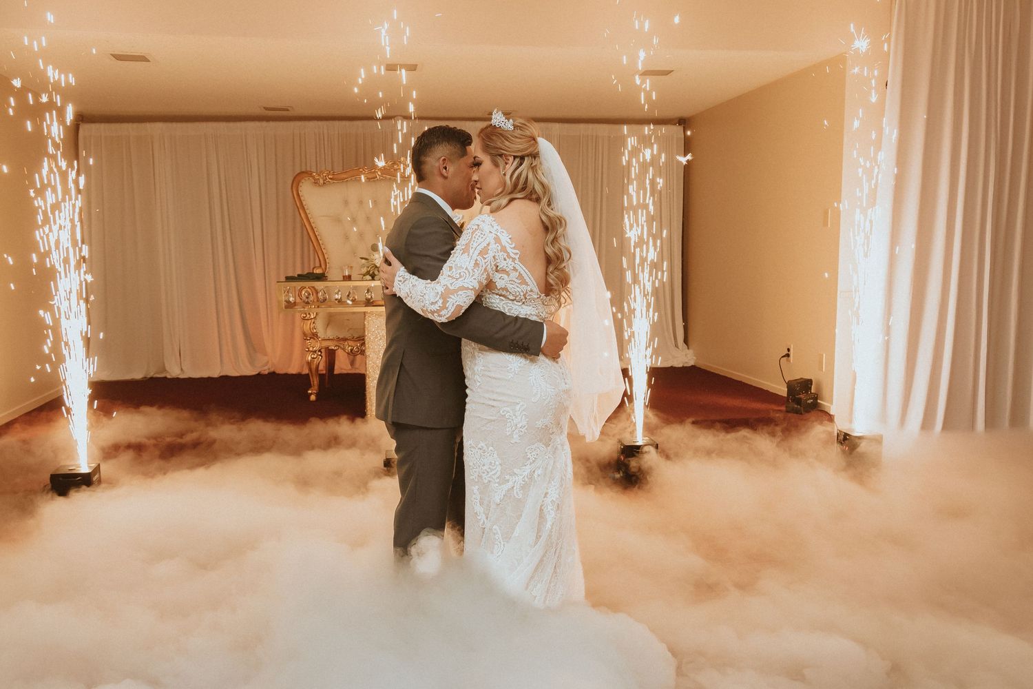Newlyweds dance together surrounded by atmospheric fog and elegant white decor.