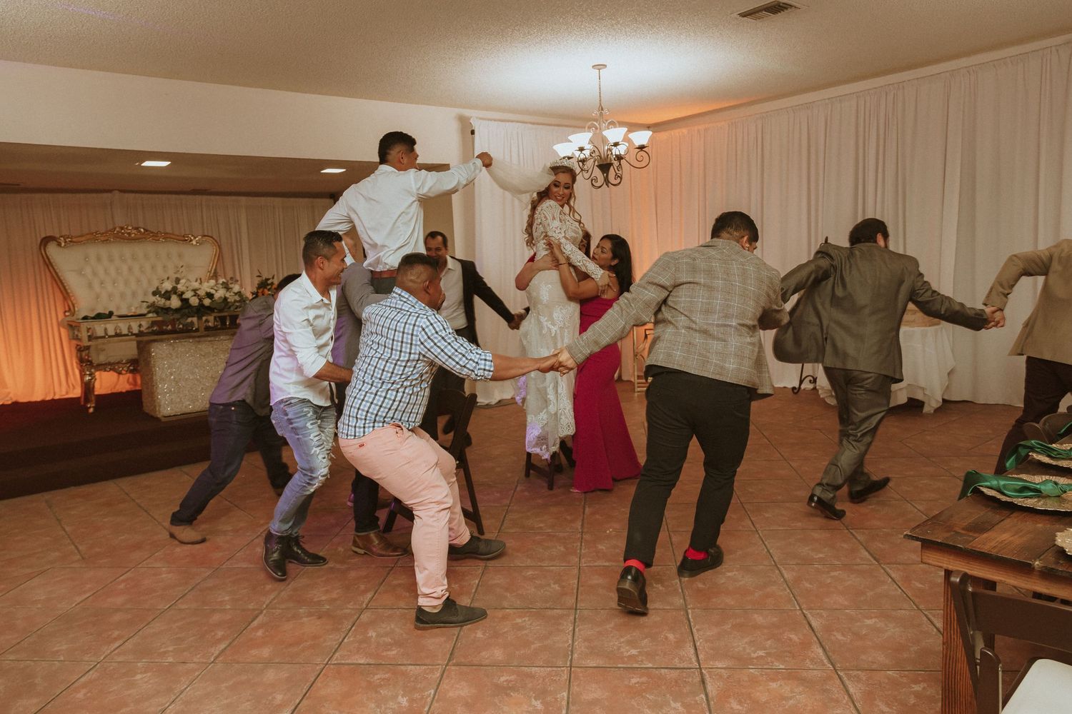 Lively group of wedding guests performing synchronized dance moves at the reception.