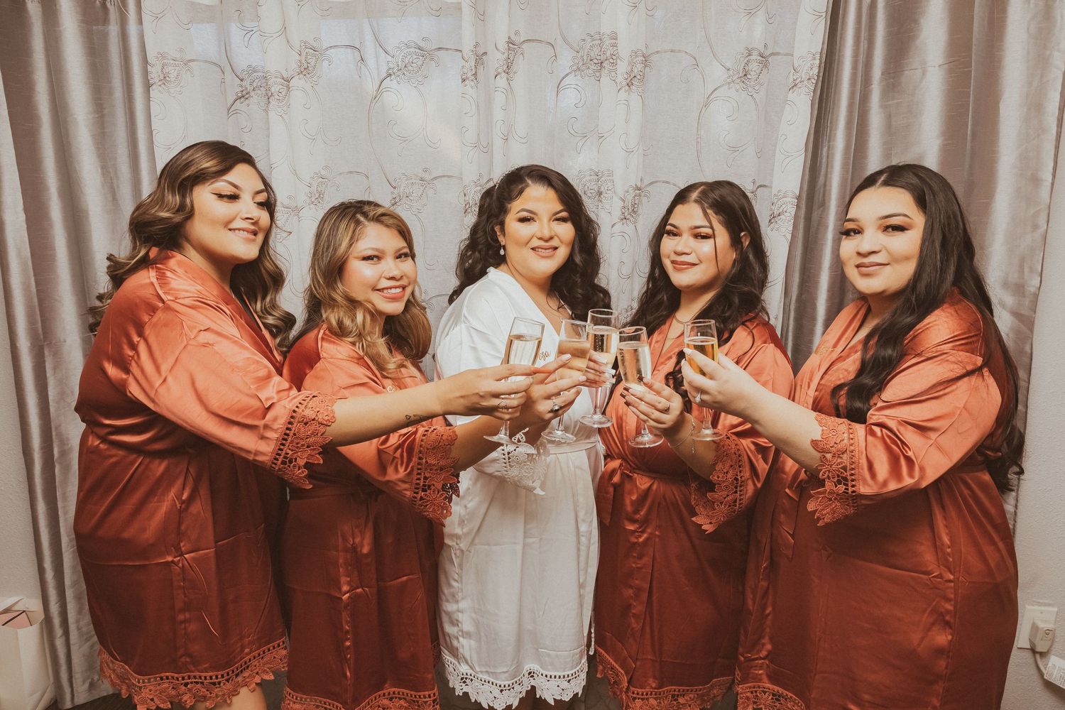Wedding party in matching burgundy robes toasts together before the ceremony.