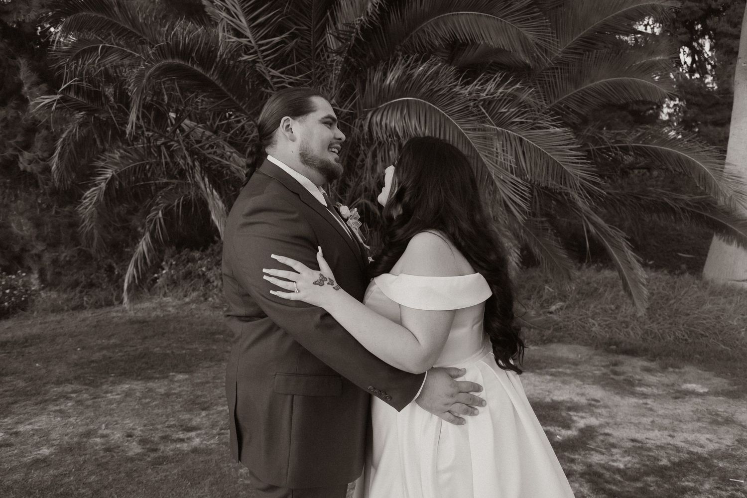 Black and white romantic wedding portrait under palm trees.