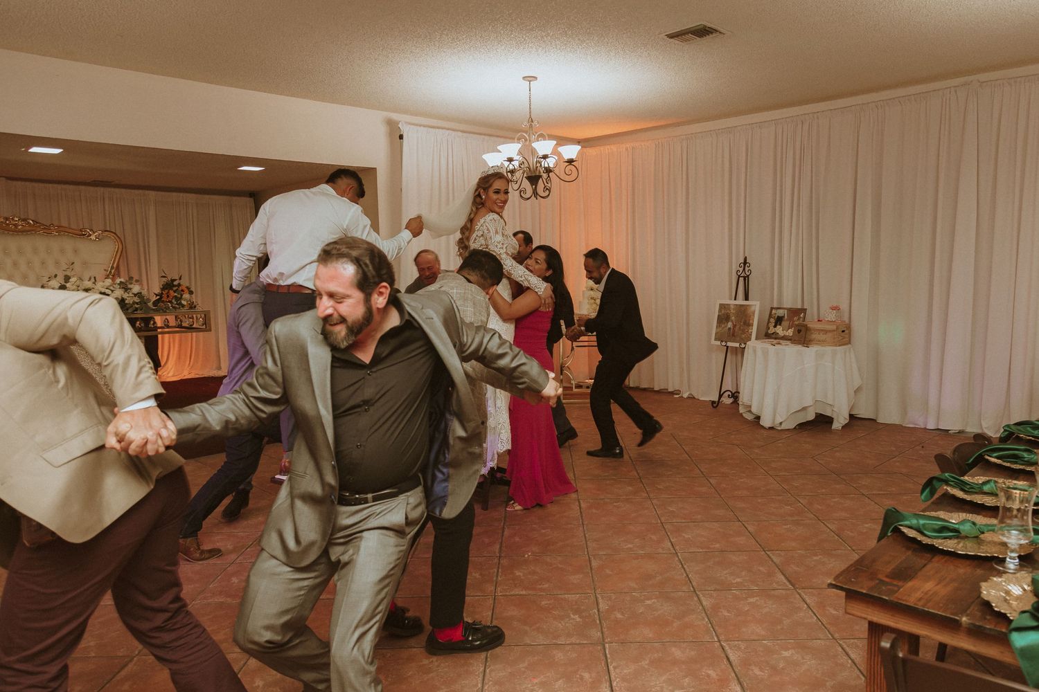 Guests dancing in a line formation during an indoor celebration with warm lighting.