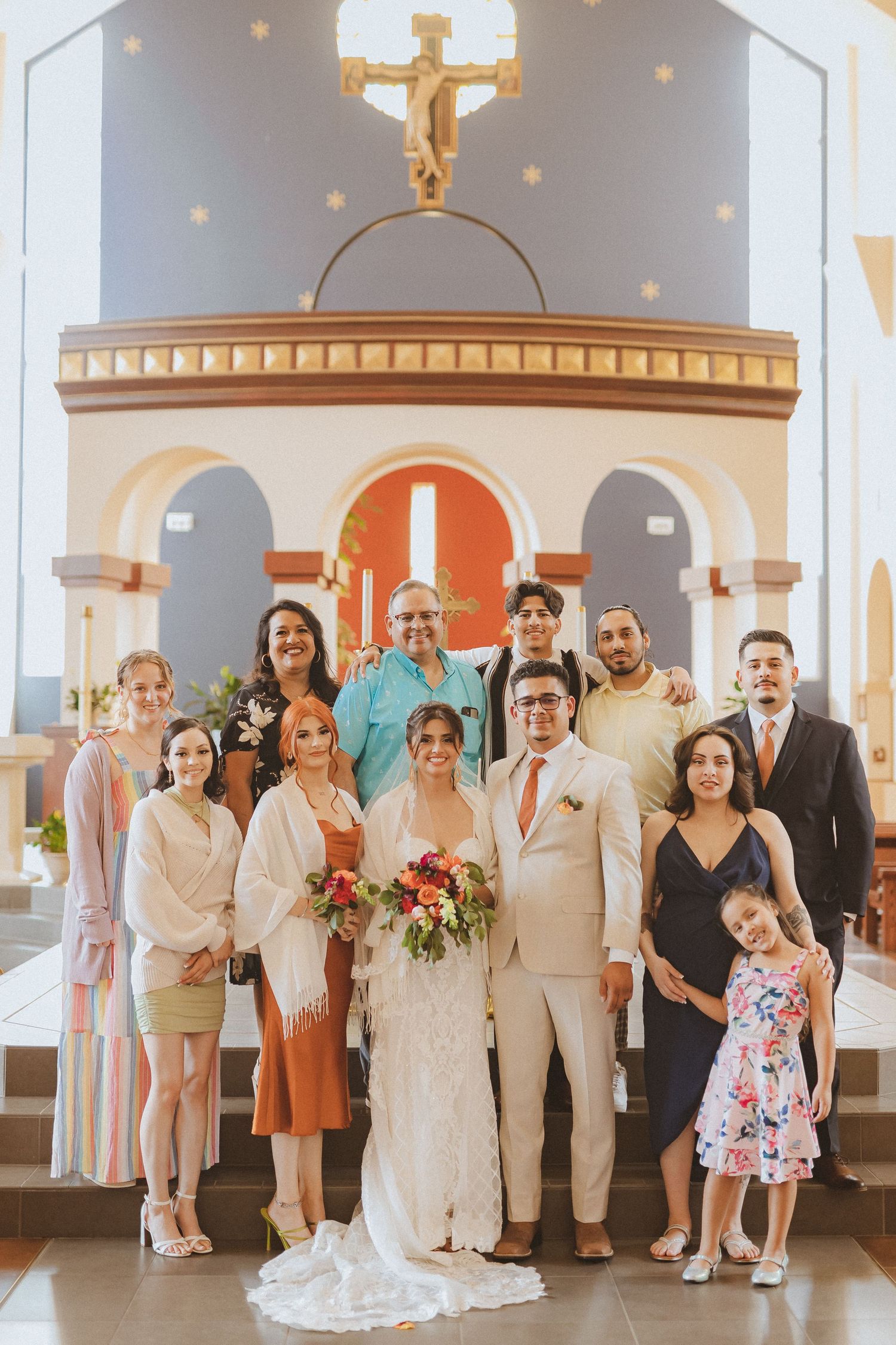 A large wedding party group photo taken at the church altar.