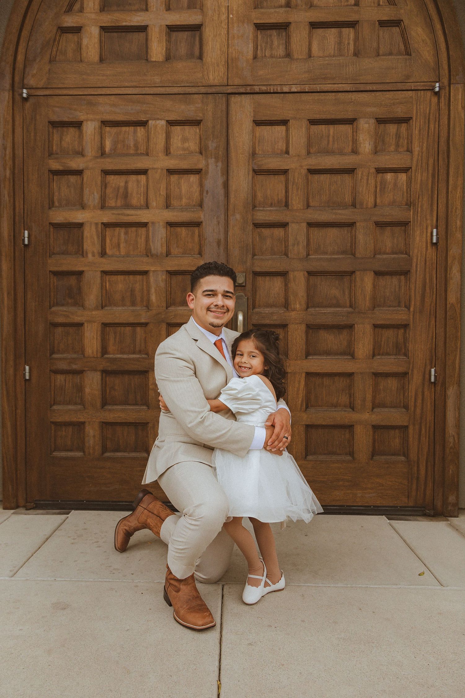 A sweet moment shared in front of an ornate wooden church door.