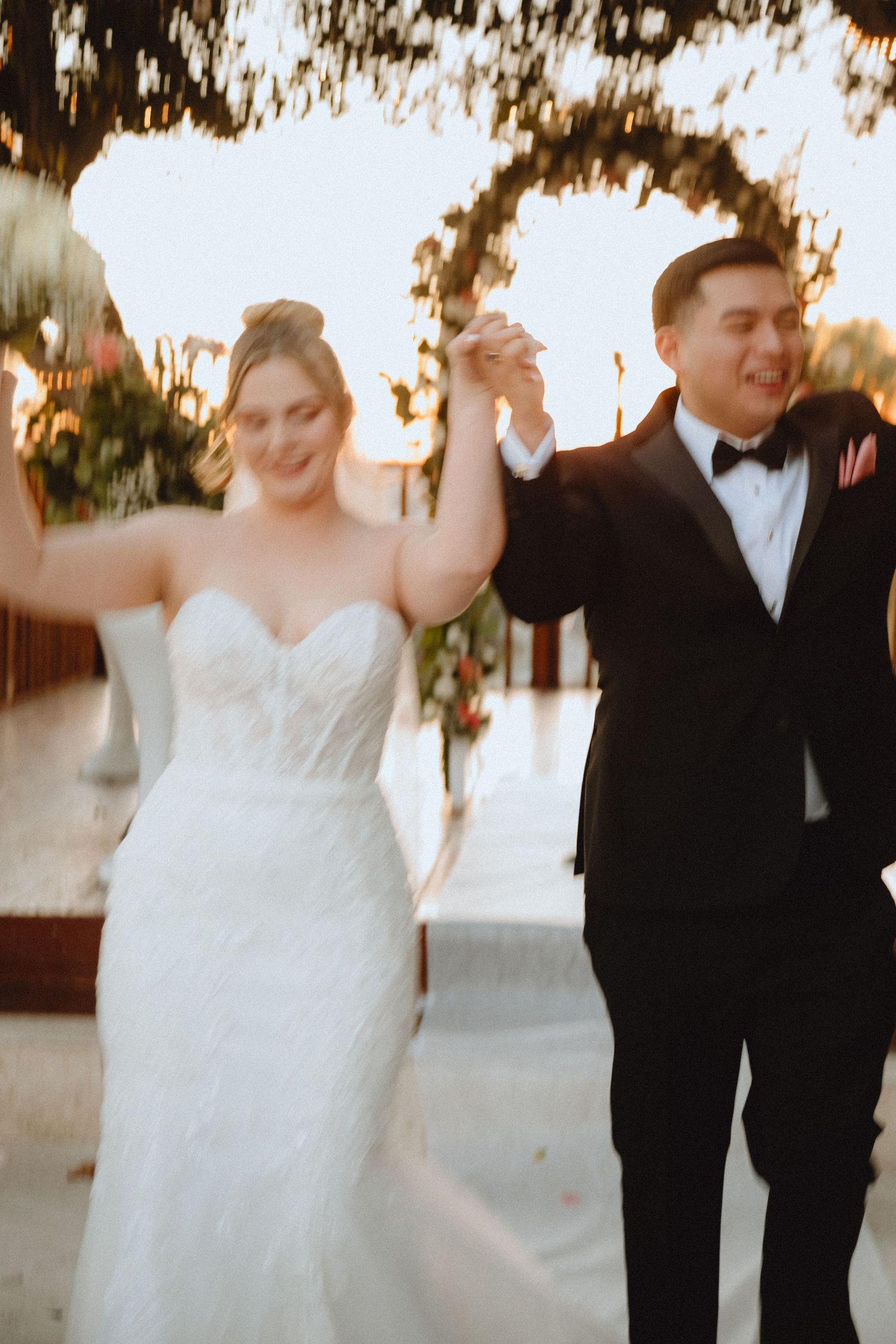 Joyful couple celebrating during their wedding reception with raised hands.