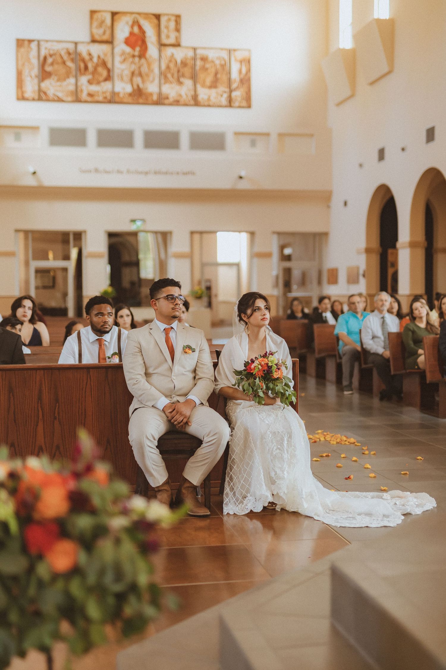 A wedding ceremony in a bright church sanctuary with religious artwork and wooden pews.