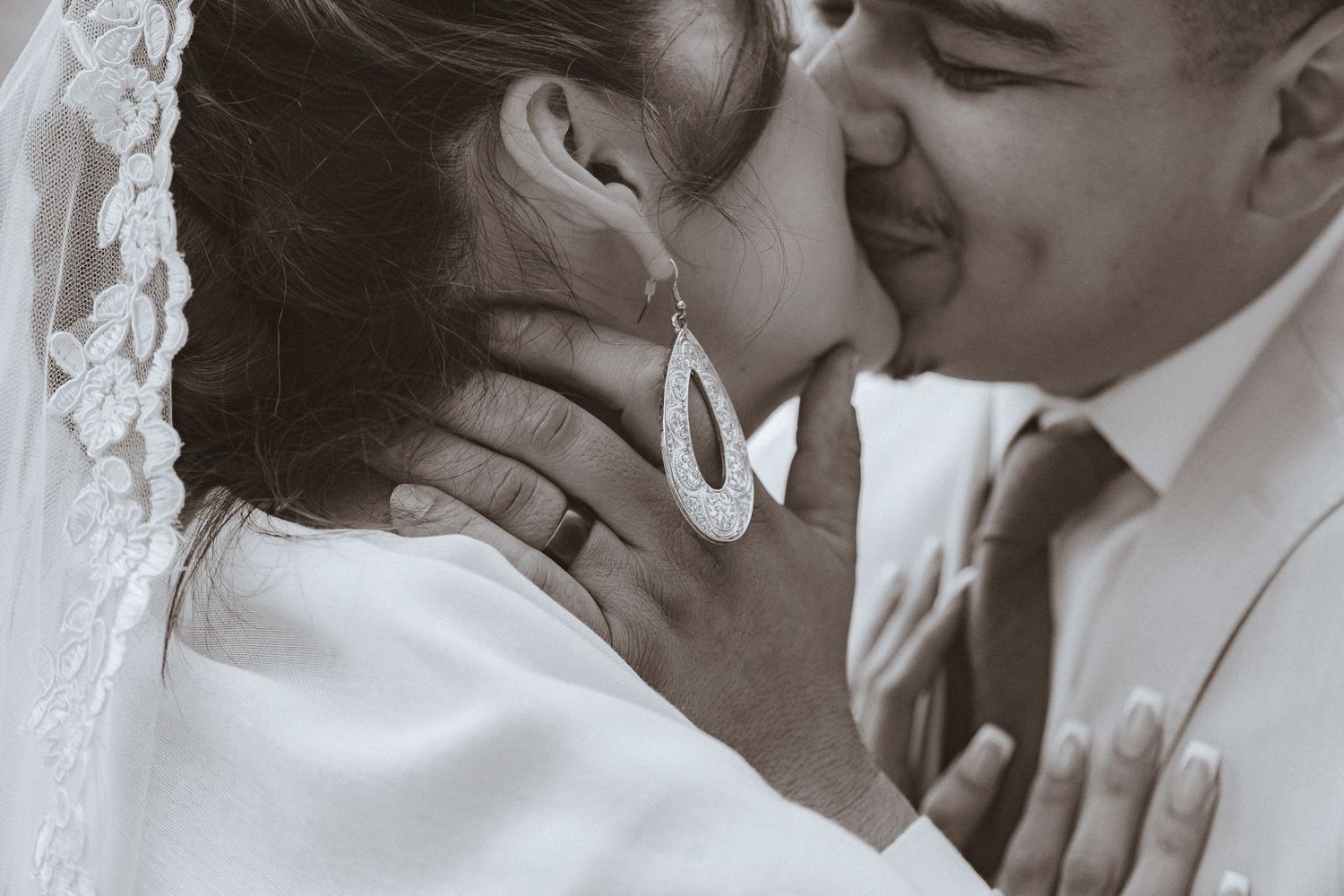 An intimate black and white moment between newlyweds sharing a tender kiss.