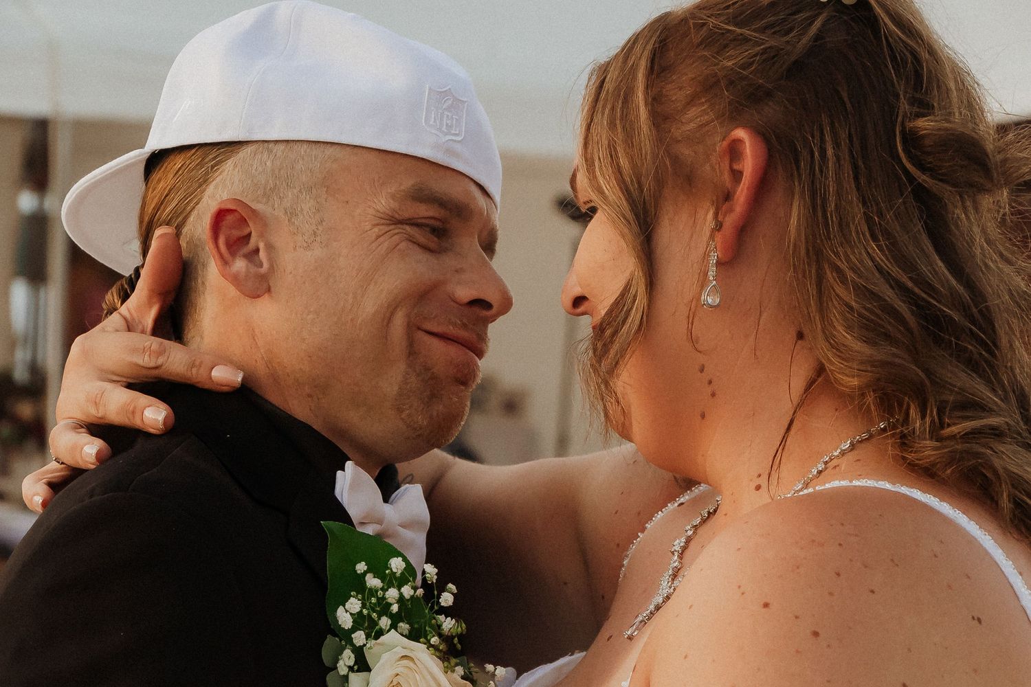 Close-up of a loving wedding embrace outdoors with soft natural lighting.