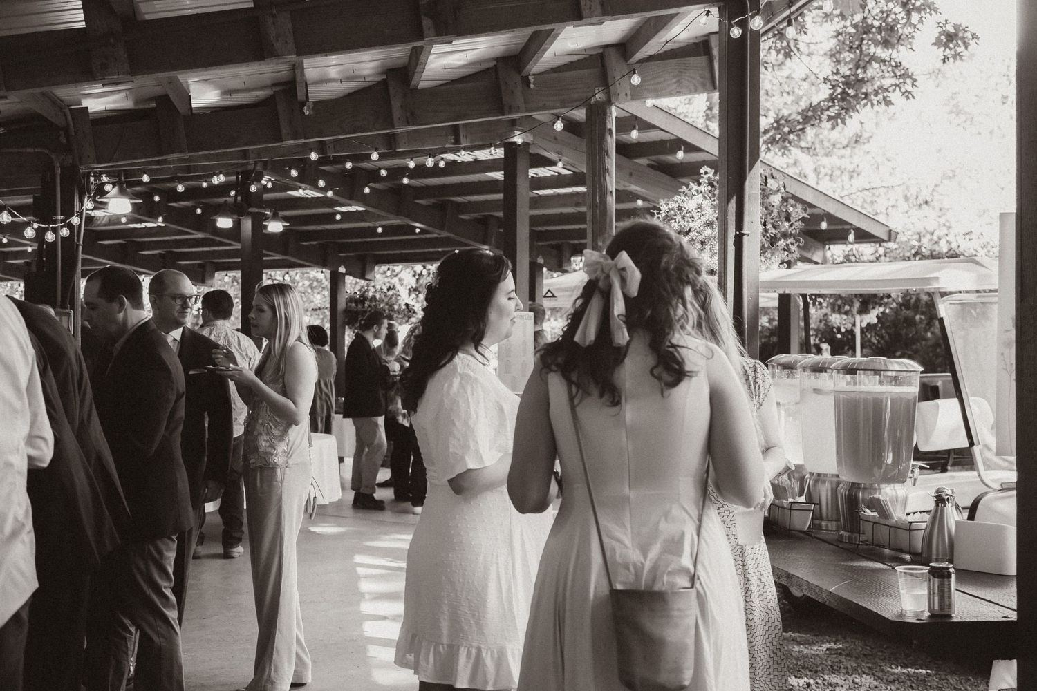 Wedding guests mingle under a covered outdoor patio area during a reception.