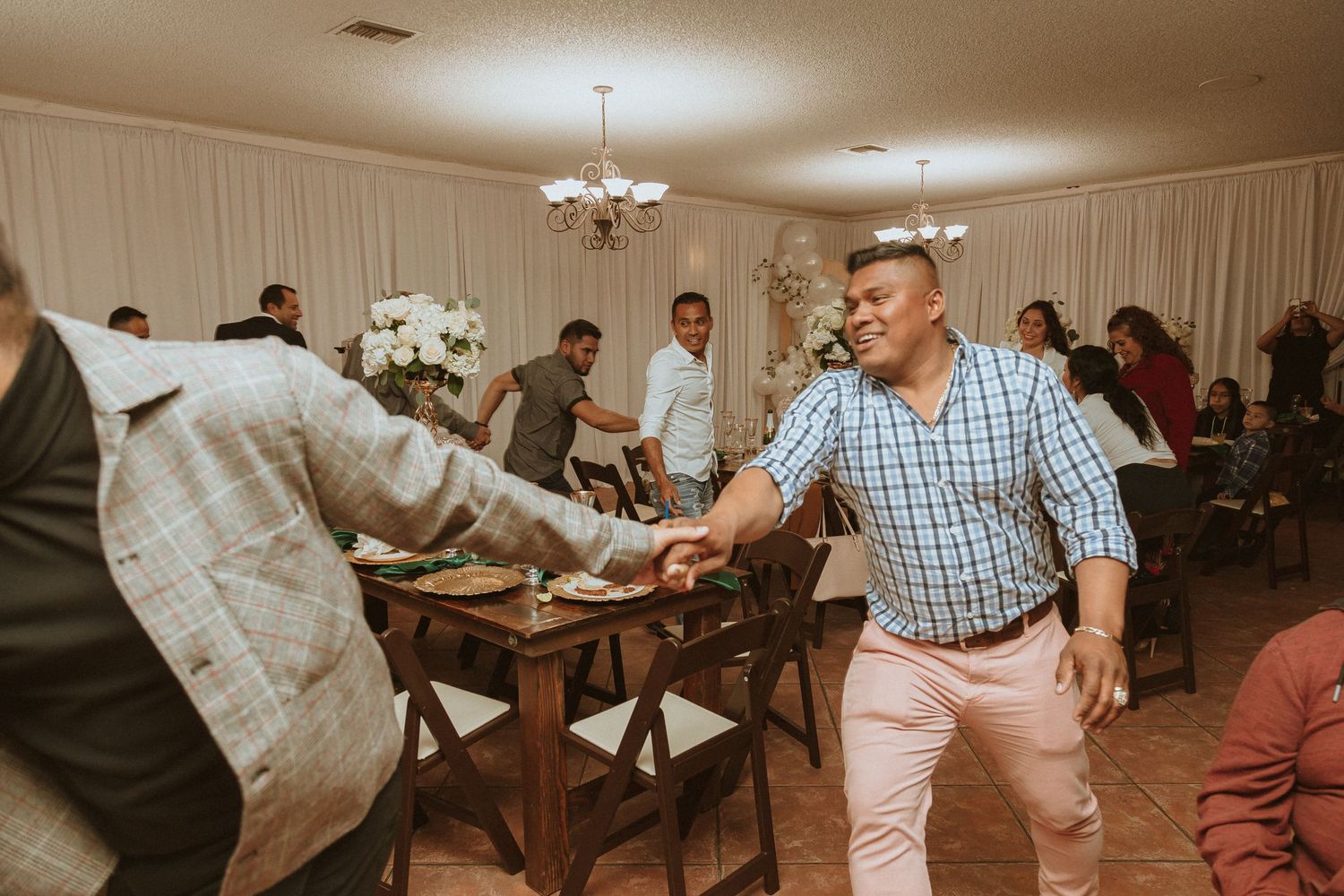 Casual reception scene with guests dancing and socializing in a decorated venue.
