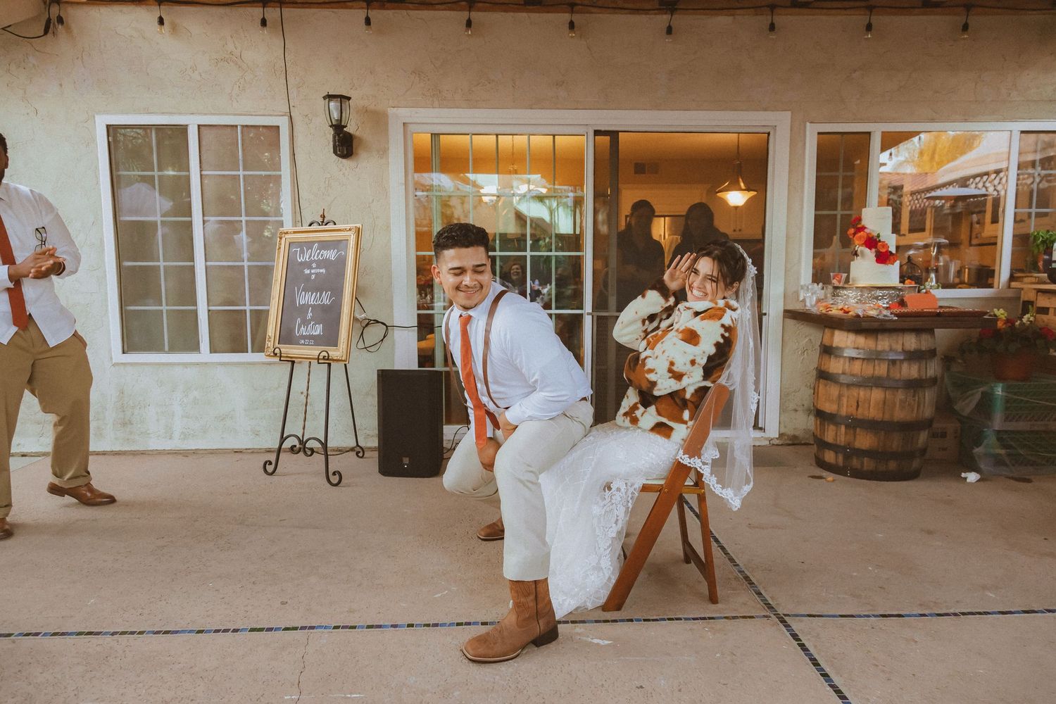 A couple performs a fun dipping dance move at an outdoor wedding reception near wooden barrels.