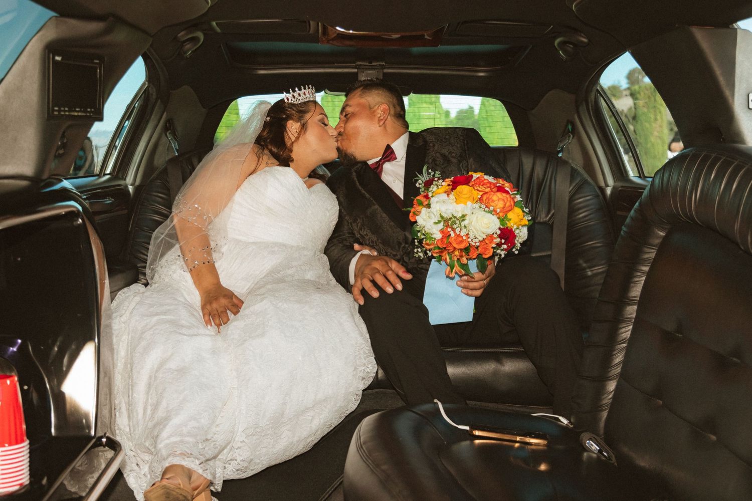 Newlyweds share an intimate moment in the back seat of their wedding limousine.