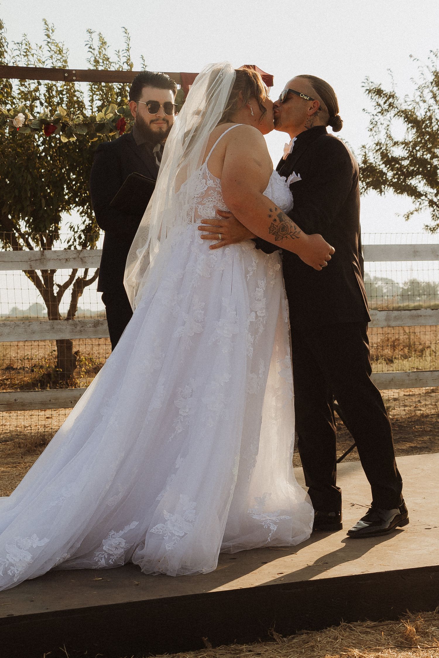 A joyful celebration during a wedding ceremony under a wooden arch with red draping.