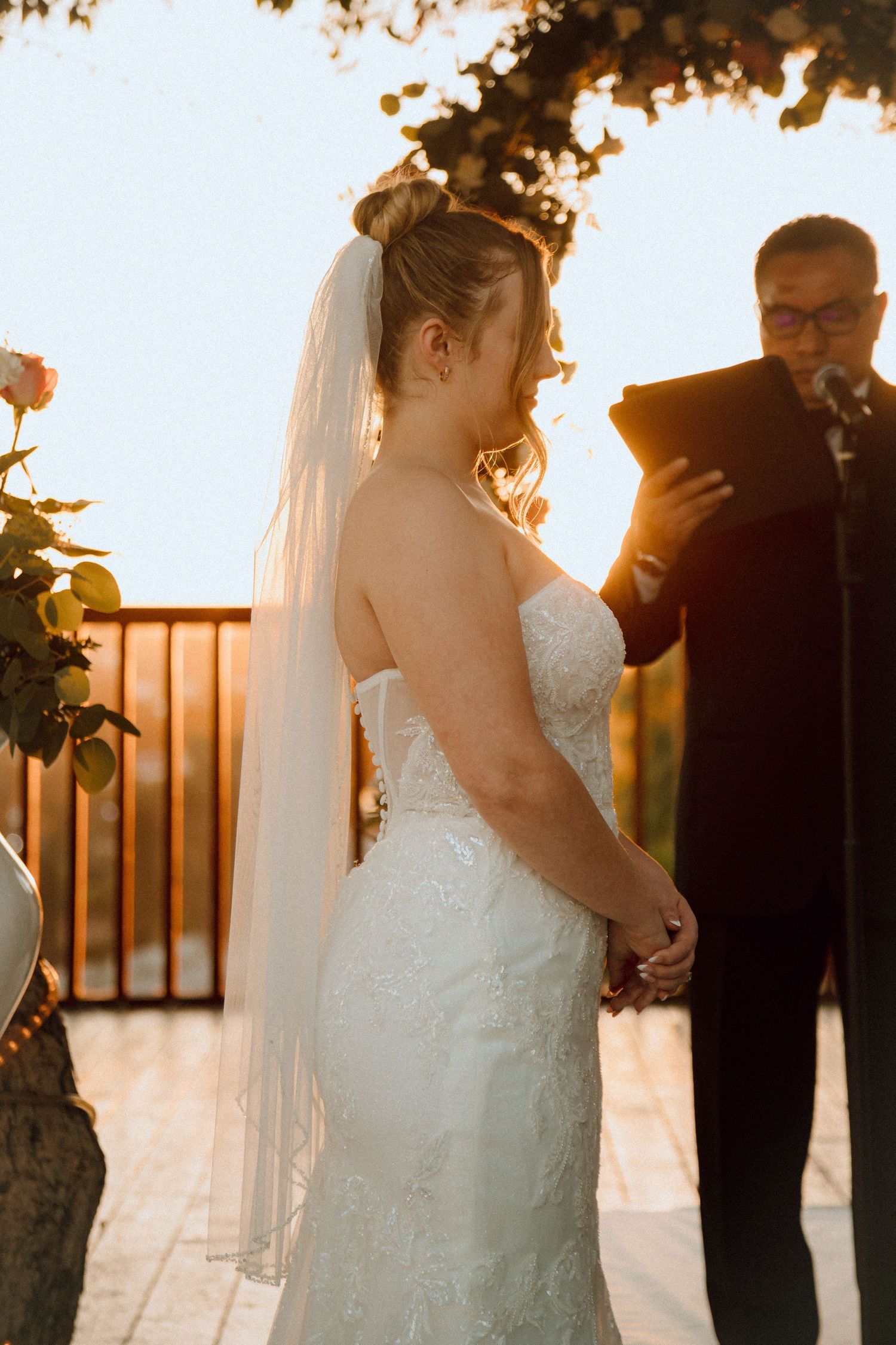 Golden hour wedding ceremony with sunlight streaming through trees and decorative details.