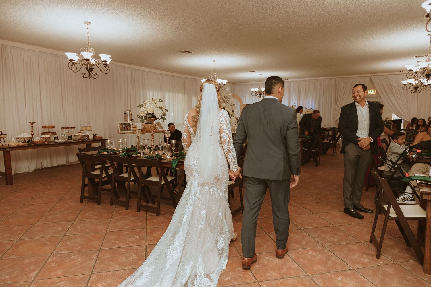 A view of a wedding reception room with terra cotta flooring and white-draped walls.