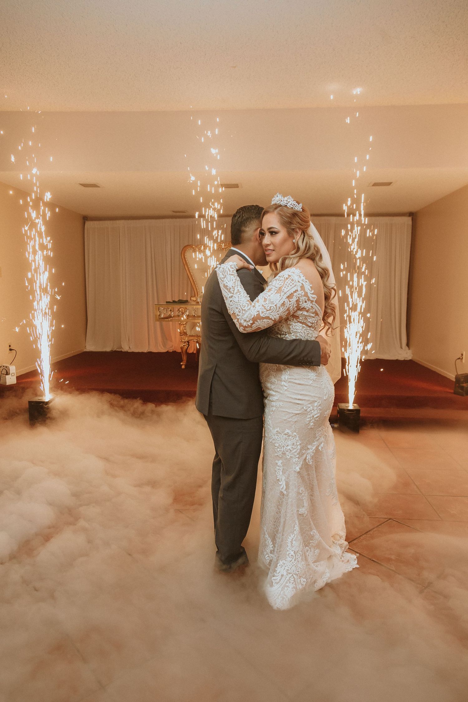A couple dances intimately on their wedding day with cold sparkler fountains creating a magical atmosphere.