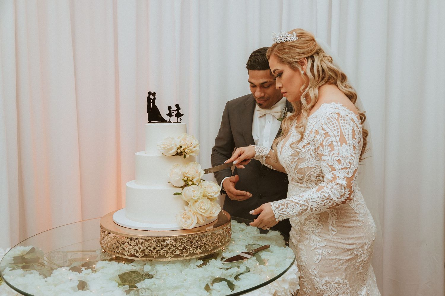 Couple preparing to cut their traditional white tiered wedding cake together.