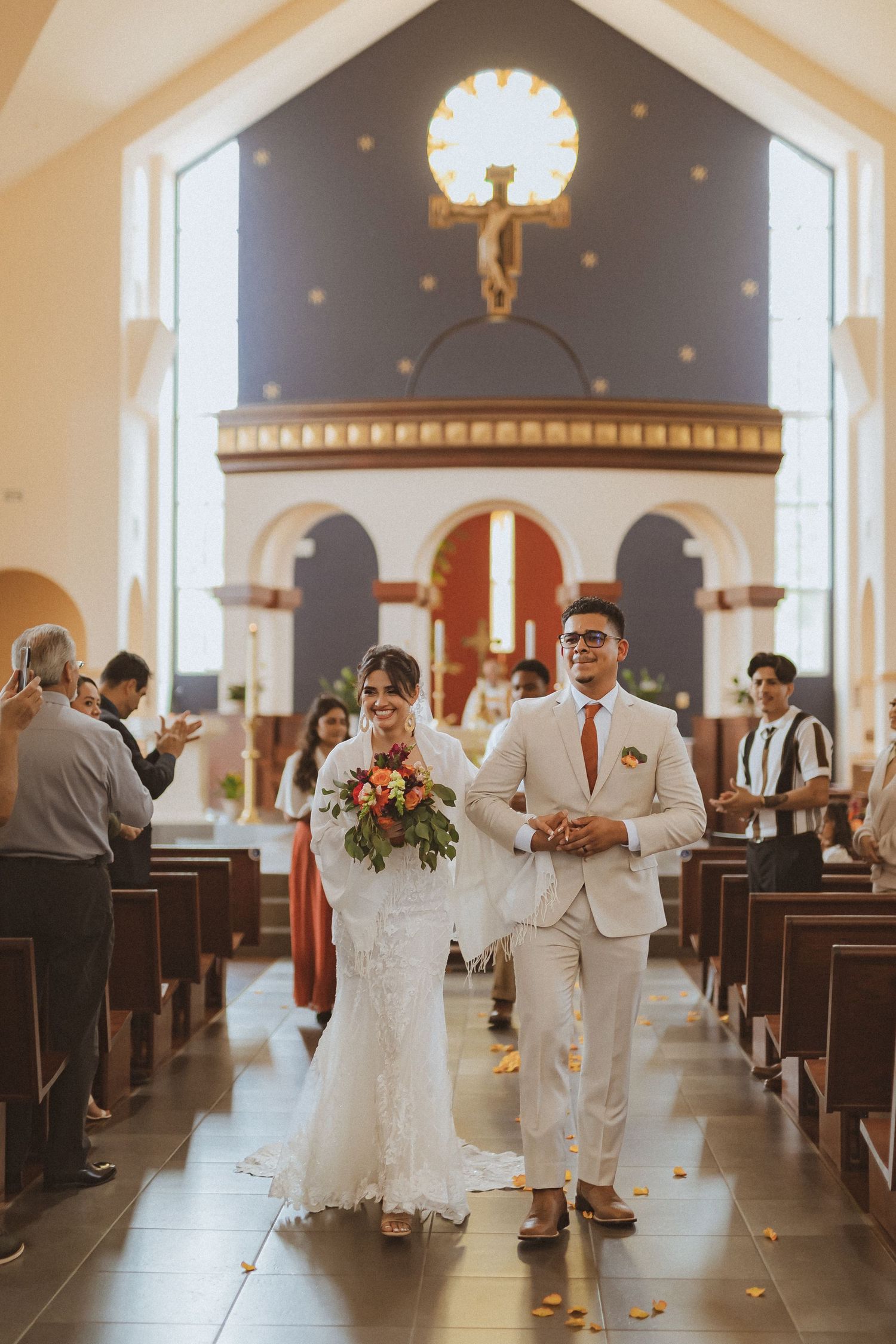 Newlyweds walking down the church aisle while guests watch from the pews.