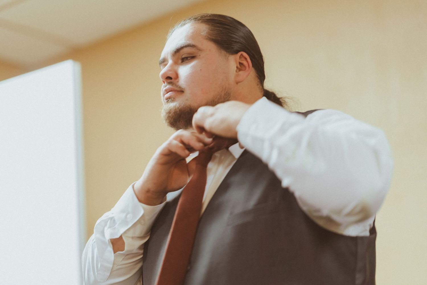 Person in formal attire adjusting their necktie while getting ready.