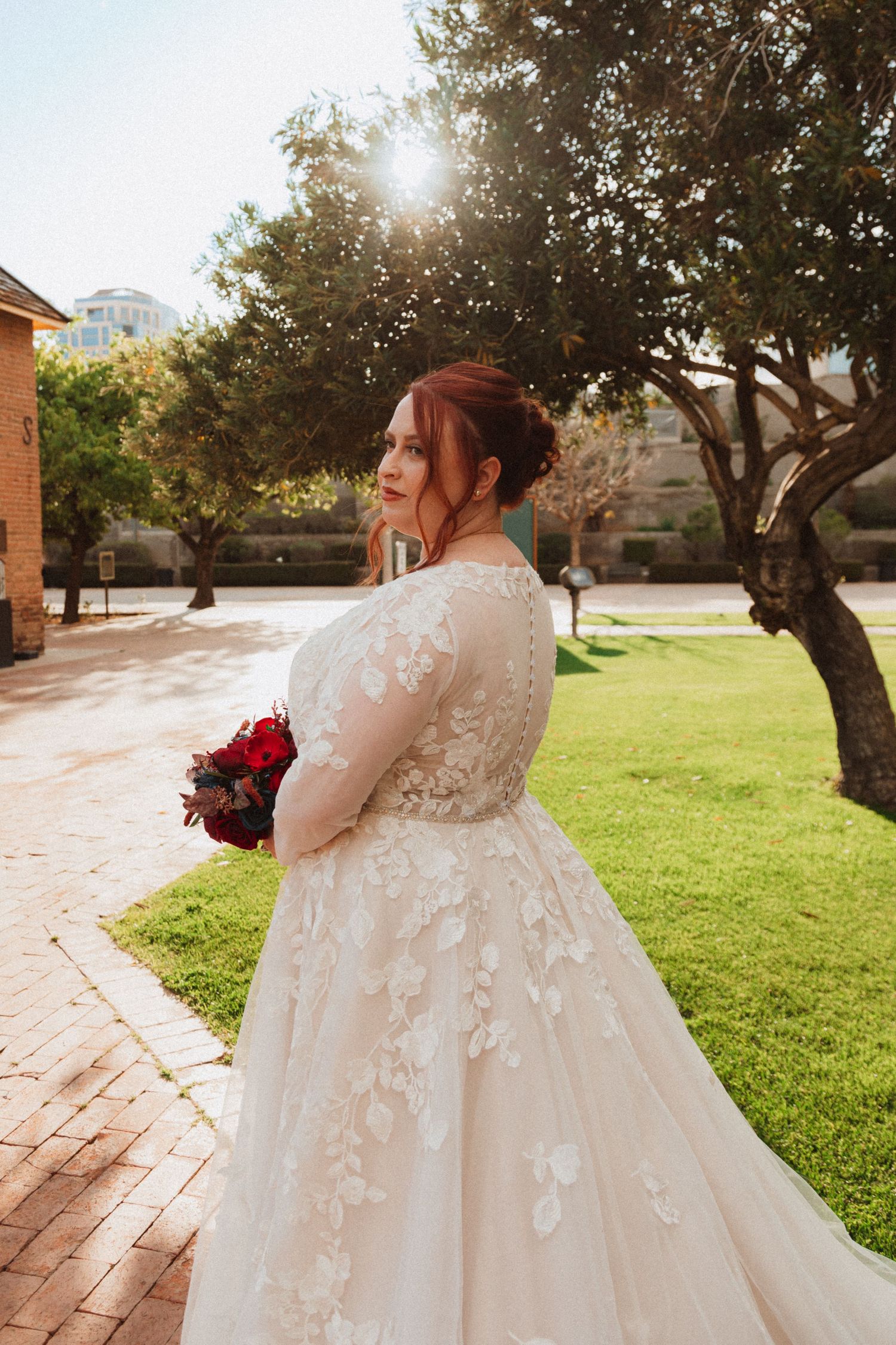 A wedding dress with delicate lace details and long train photographed in golden sunlight.