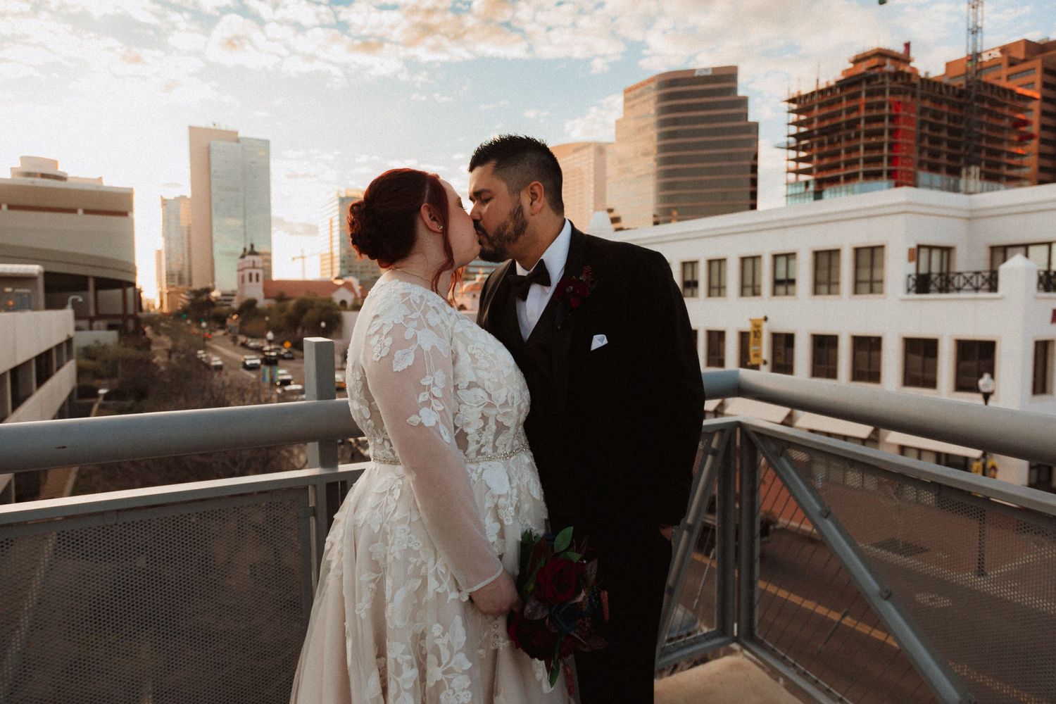 Romantic rooftop wedding portrait with city skyline and construction in background at sunset.