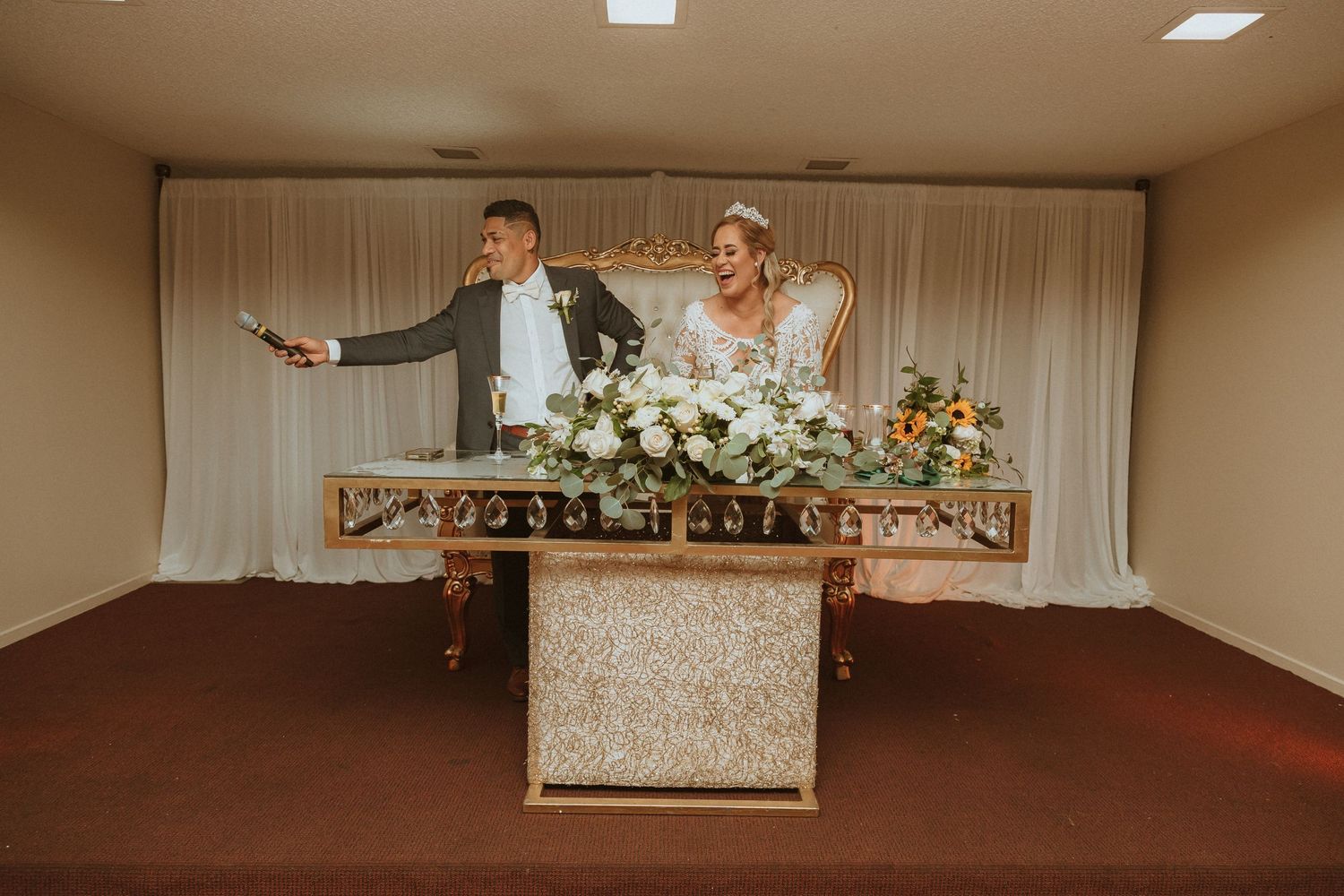 Fun reception moment captured as couple dances behind their decorated sweetheart table.