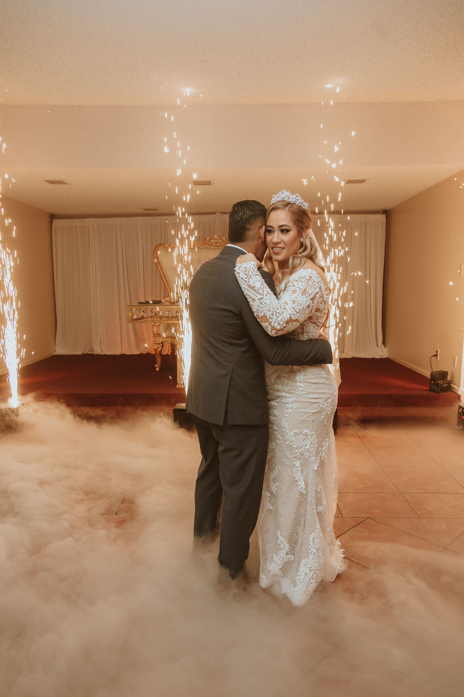 Newlyweds share their first dance surrounded by sparklers and fog effects in an elegant reception venue.