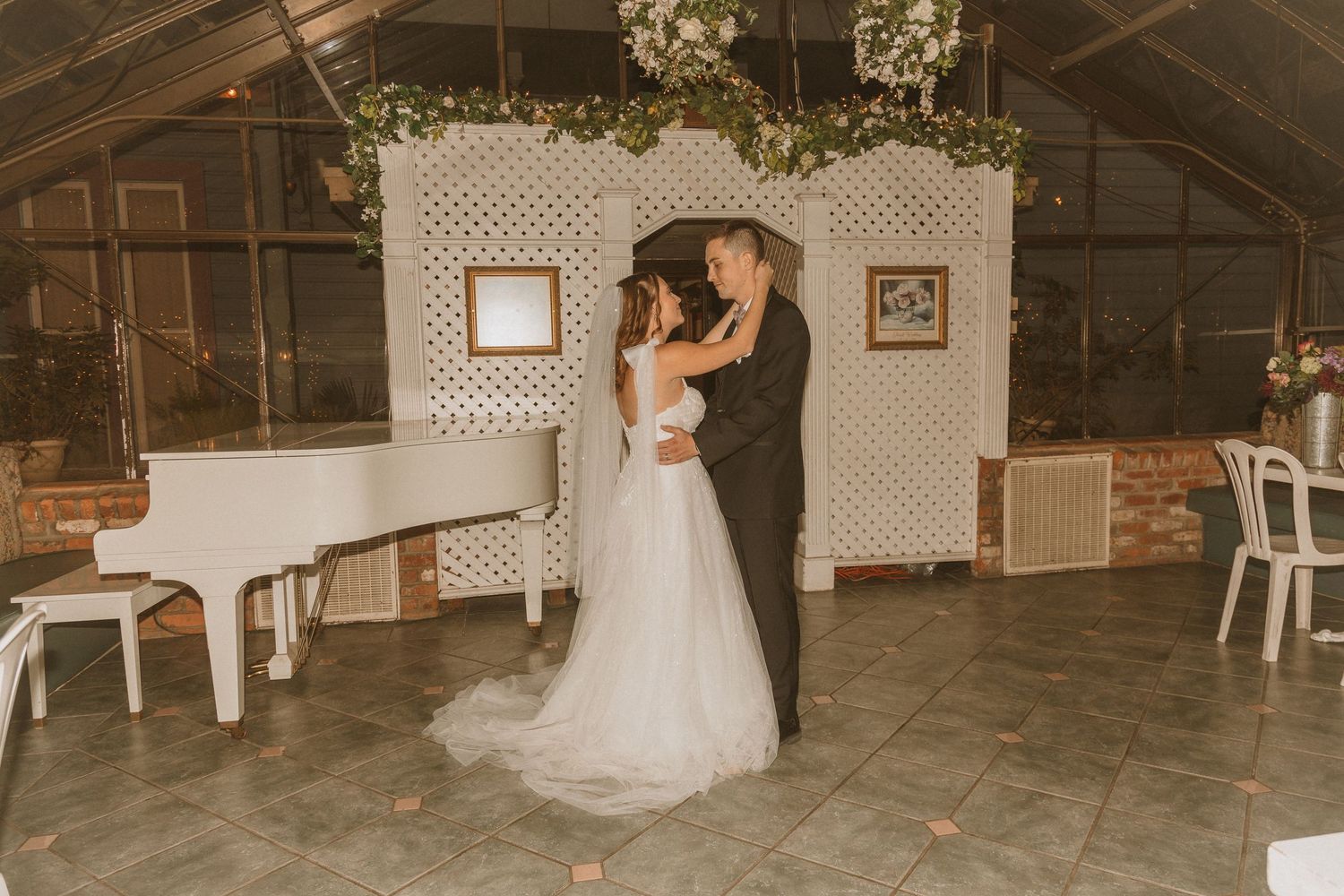 Wedding reception dance with white grand piano and lattice backdrop in vintage-style venue.
