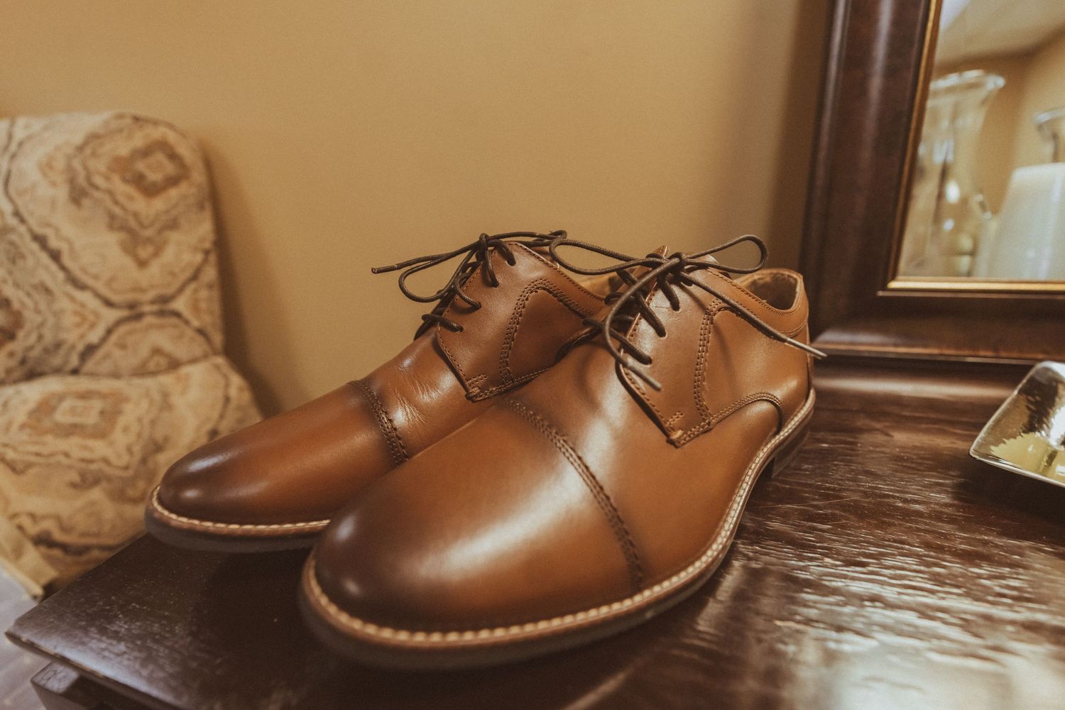 Brown leather oxford dress shoes displayed on wooden surface.