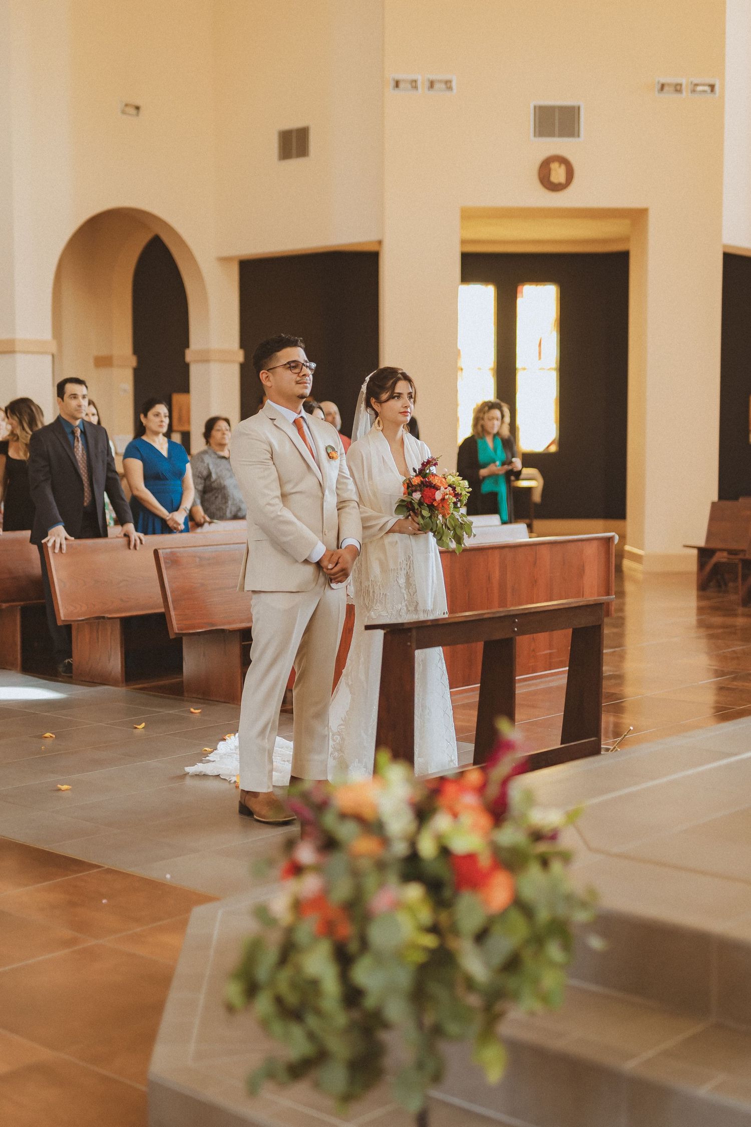 Church wedding ceremony with couple at altar and floral arrangements.
