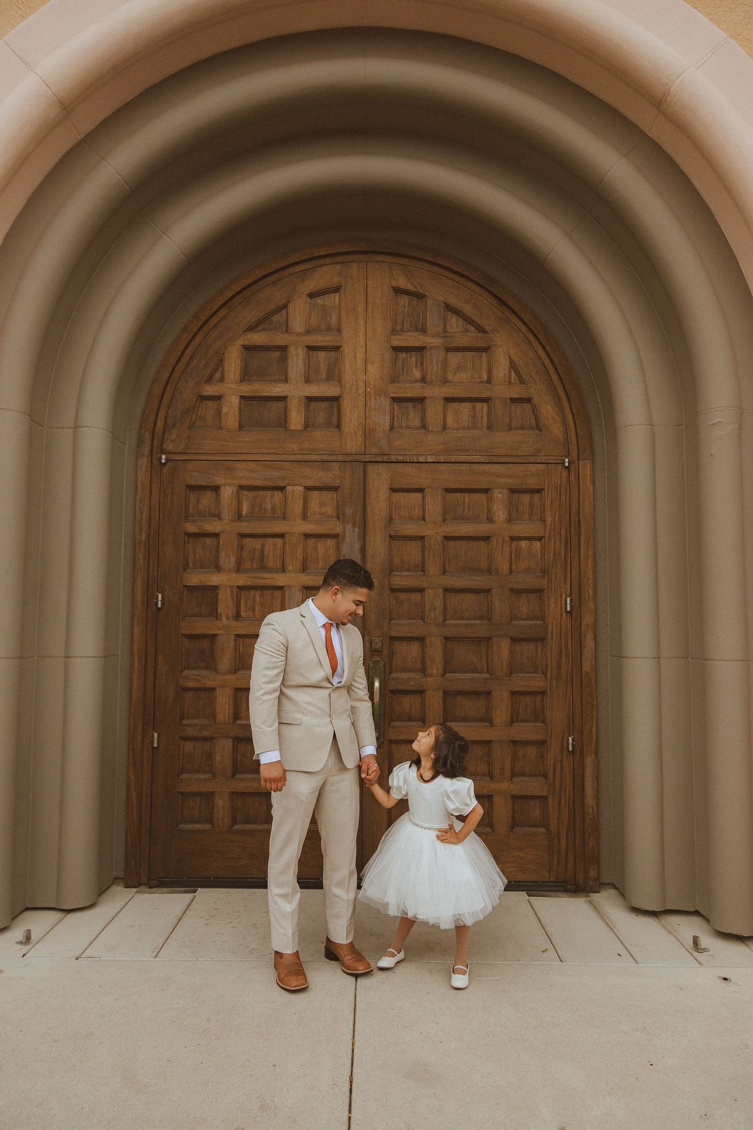 Candid wedding moment captured against architectural backdrop of wooden church doors.