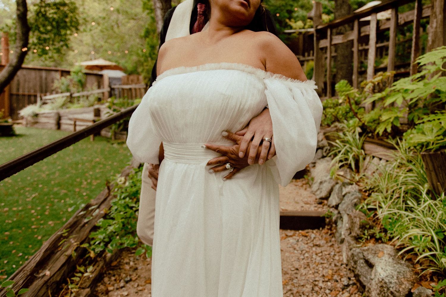 Close-up detail of an off-shoulder white wedding dress with flowing sleeves.