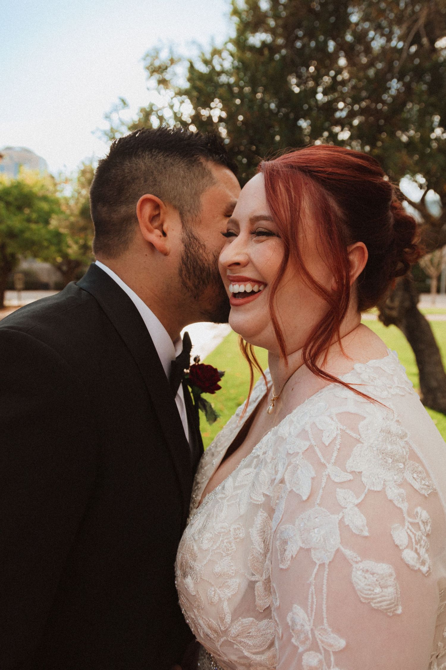 A joyful candid wedding moment captured outdoors with laughter and natural sunlight.