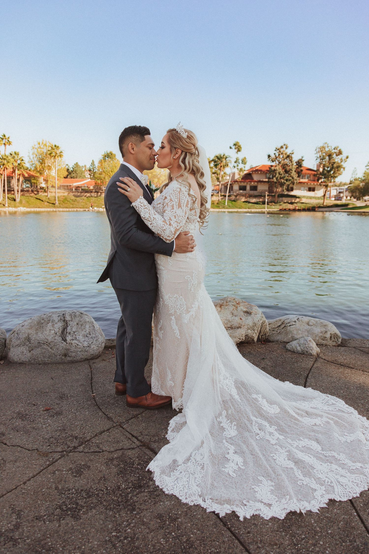 A couple kisses during their waterfront wedding ceremony with autumn scenery in the background.