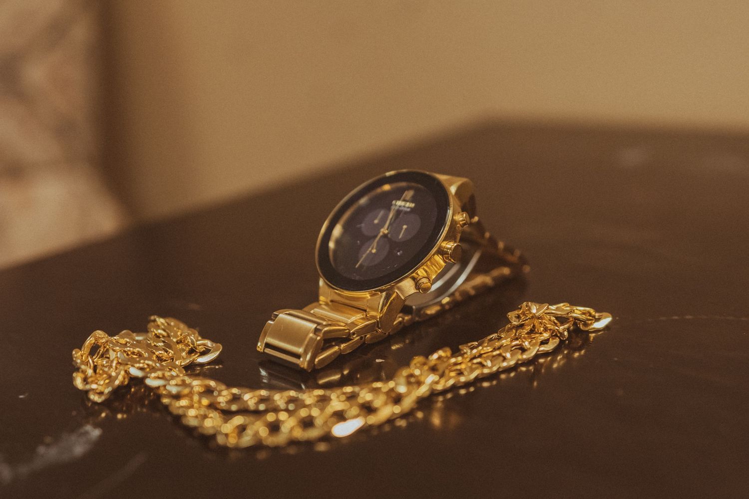 Vintage gold watch with chain displayed on dark wooden surface.
