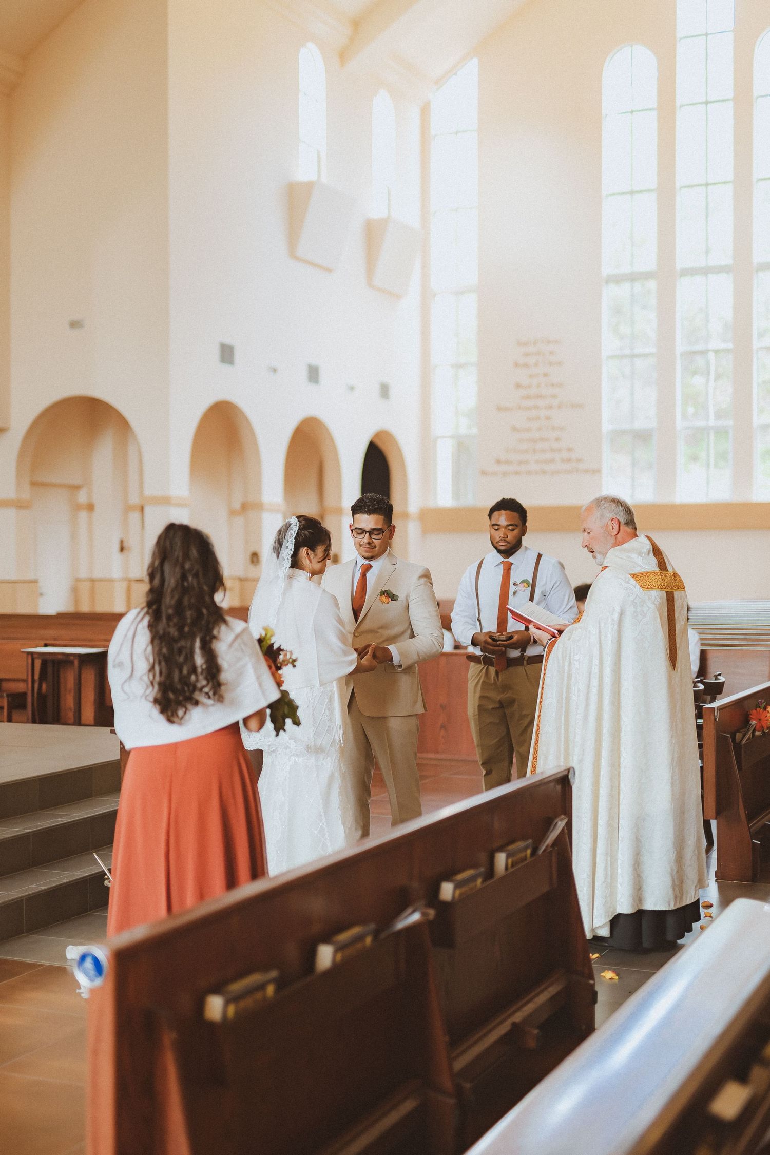A group gathers near the altar during a wedding ceremony in a bright church interior.