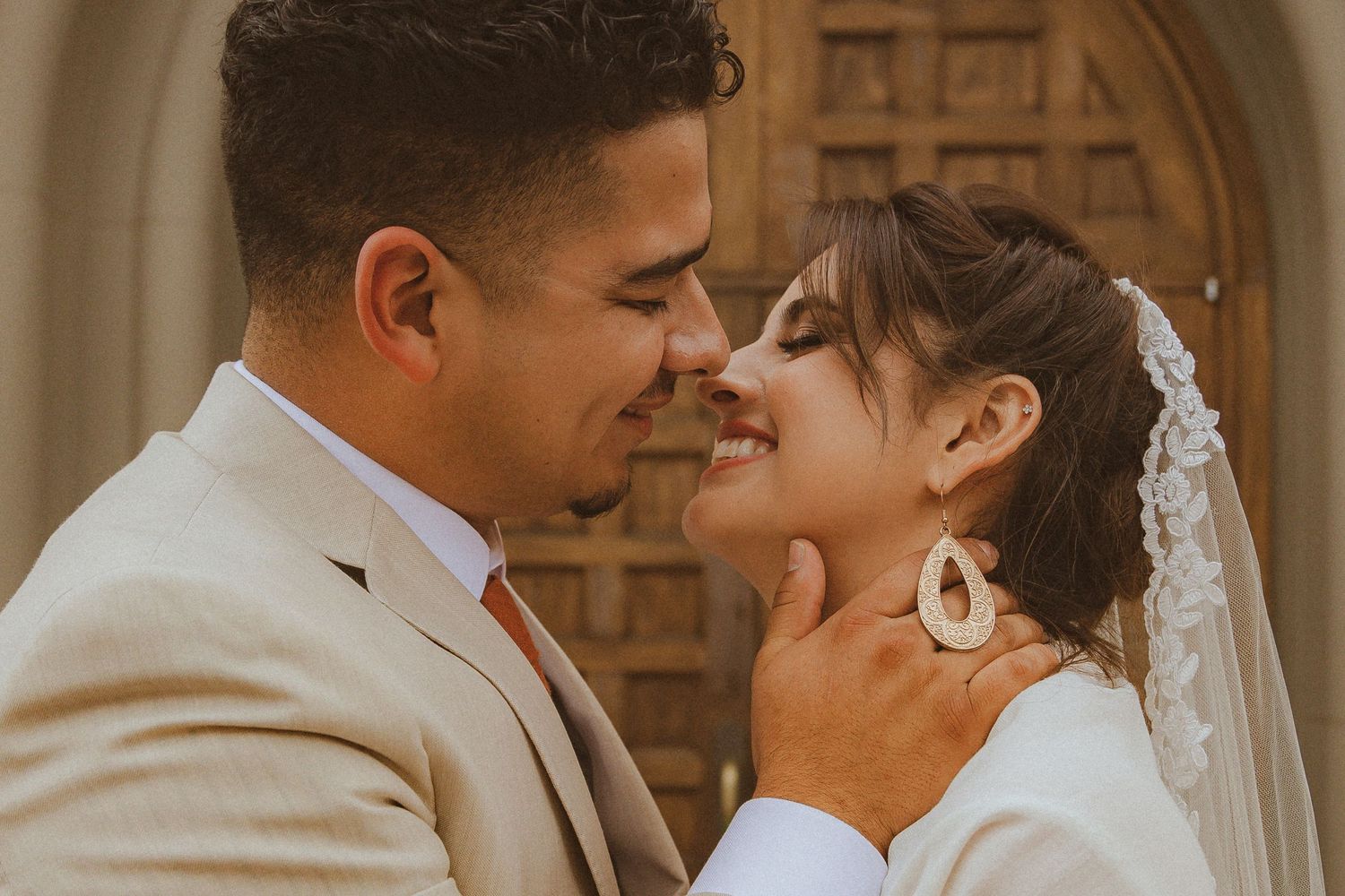 Romantic close-up of newlyweds sharing intimate moment in front of stone archway.