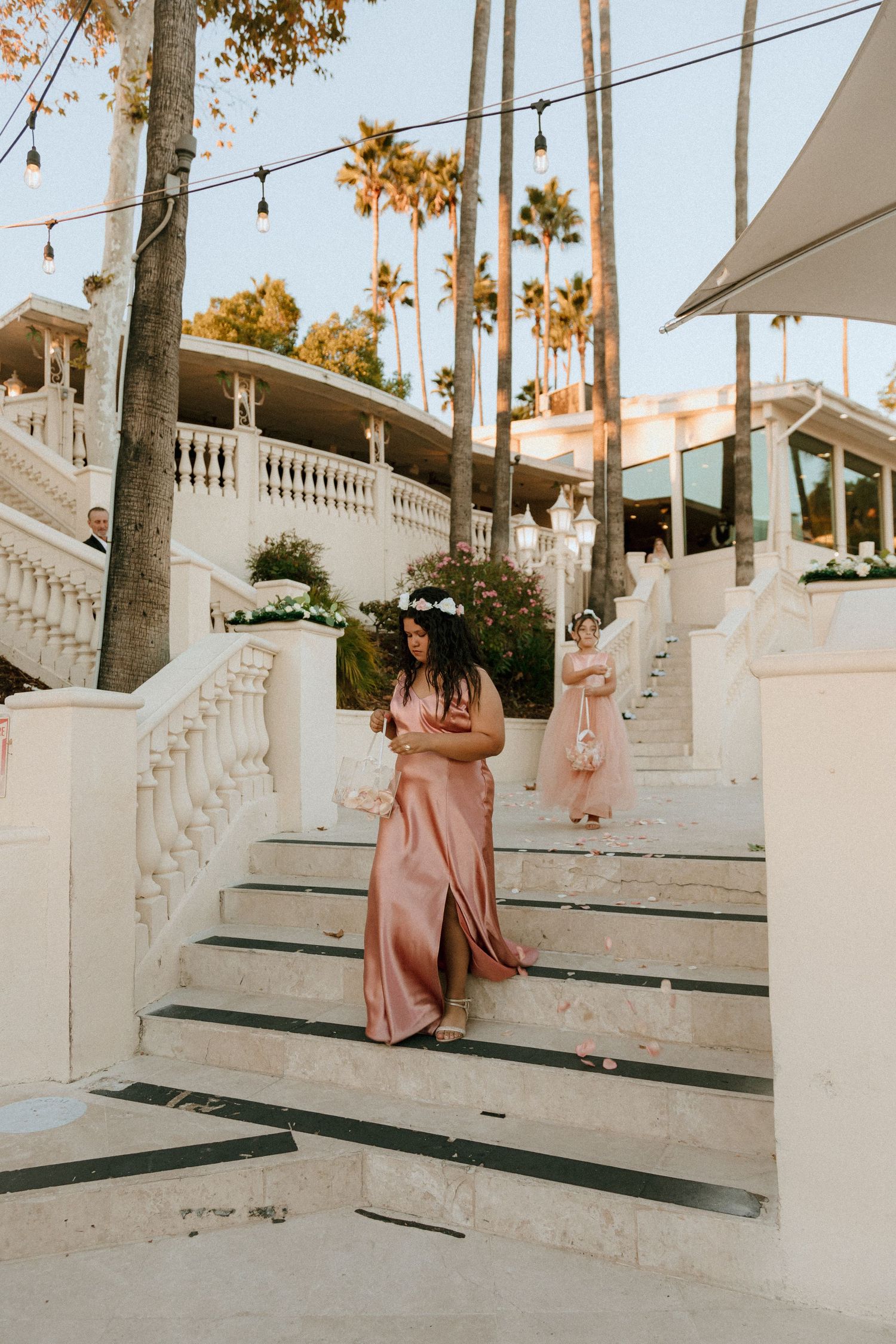 Elegant staircase with string lights and palm trees creates romantic ambiance at sunset.