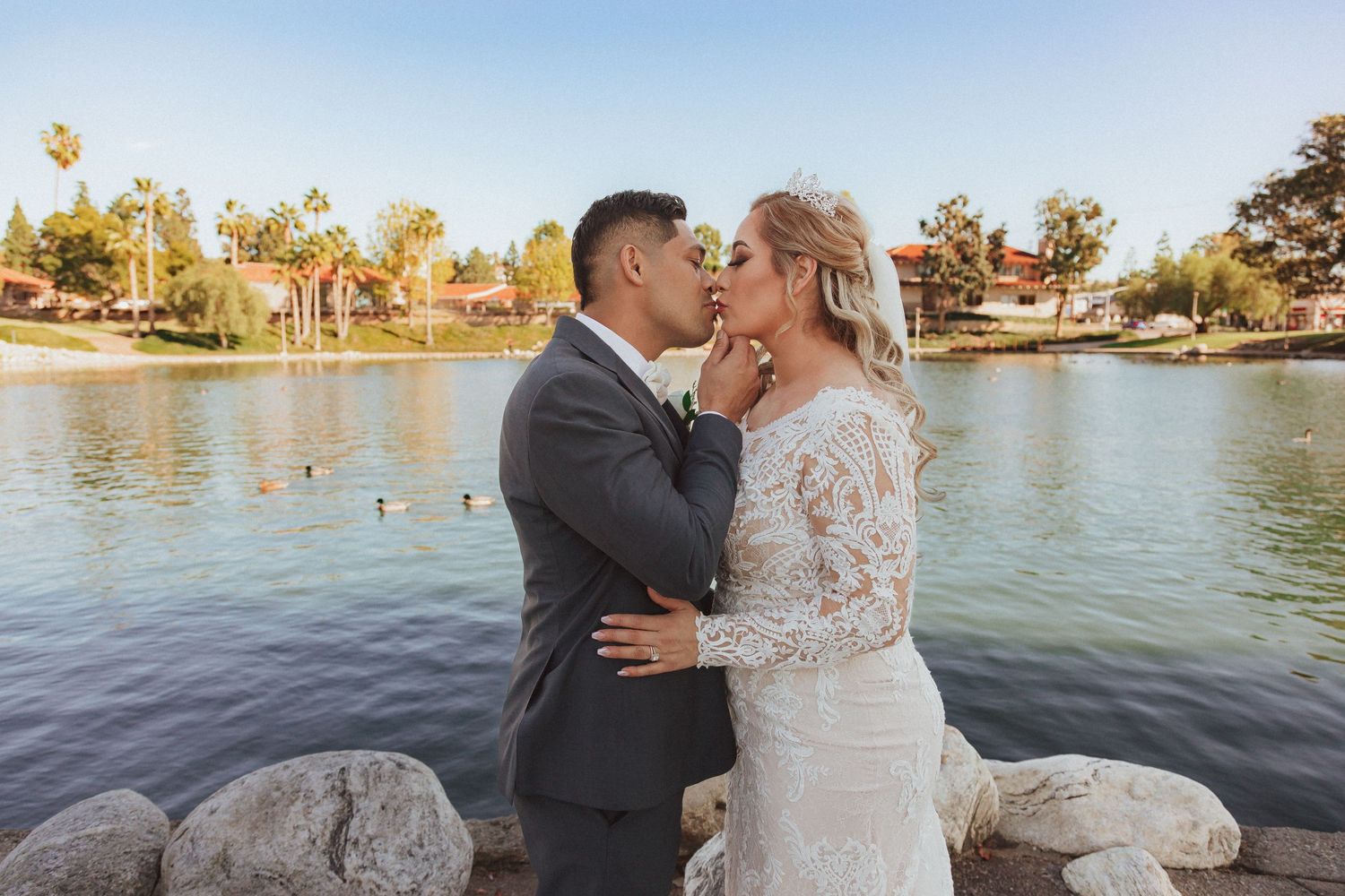 An intimate wedding moment captured by the water with lakeside homes in the background.