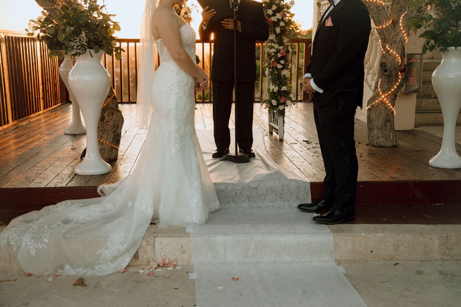 Wedding ceremony setup with elegant white floral arrangements and sunset lighting.