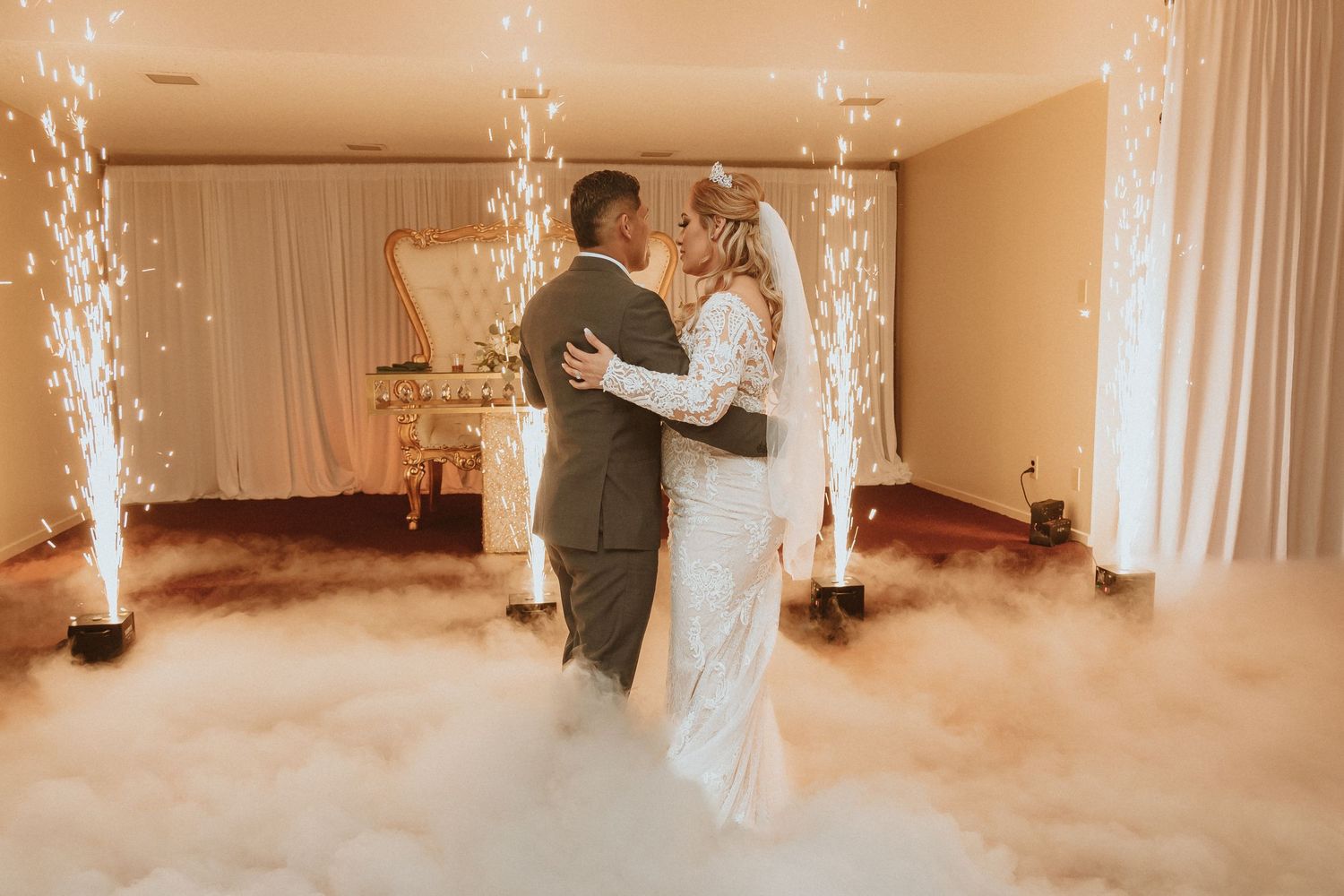 Wedding couple dances in romantic setting with low fog and sparkler effects.